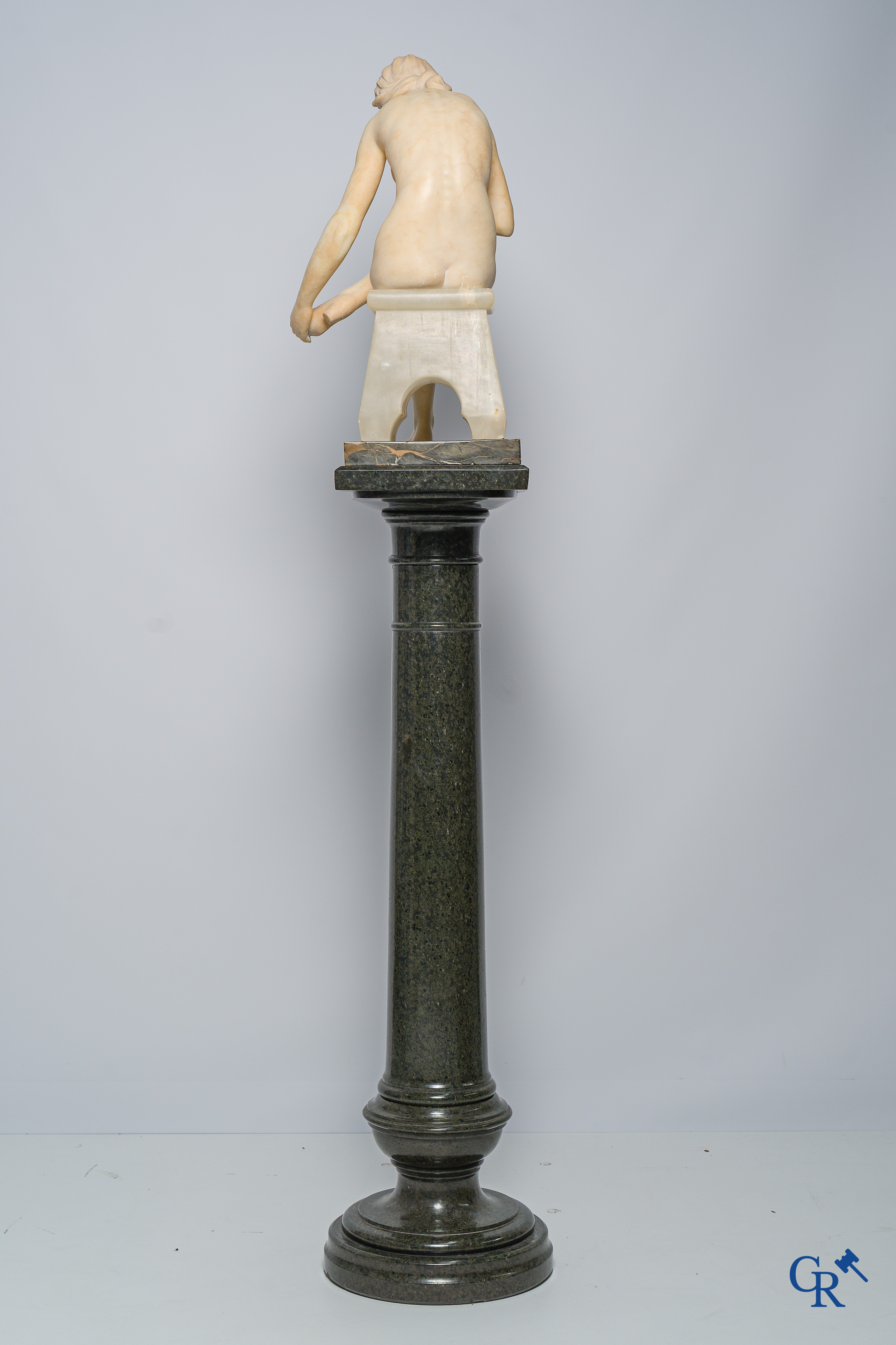 Art Nouveau. Marble statue of a sitting young lady on a chair. Associated pedestal in serpentine. Circa 1910.