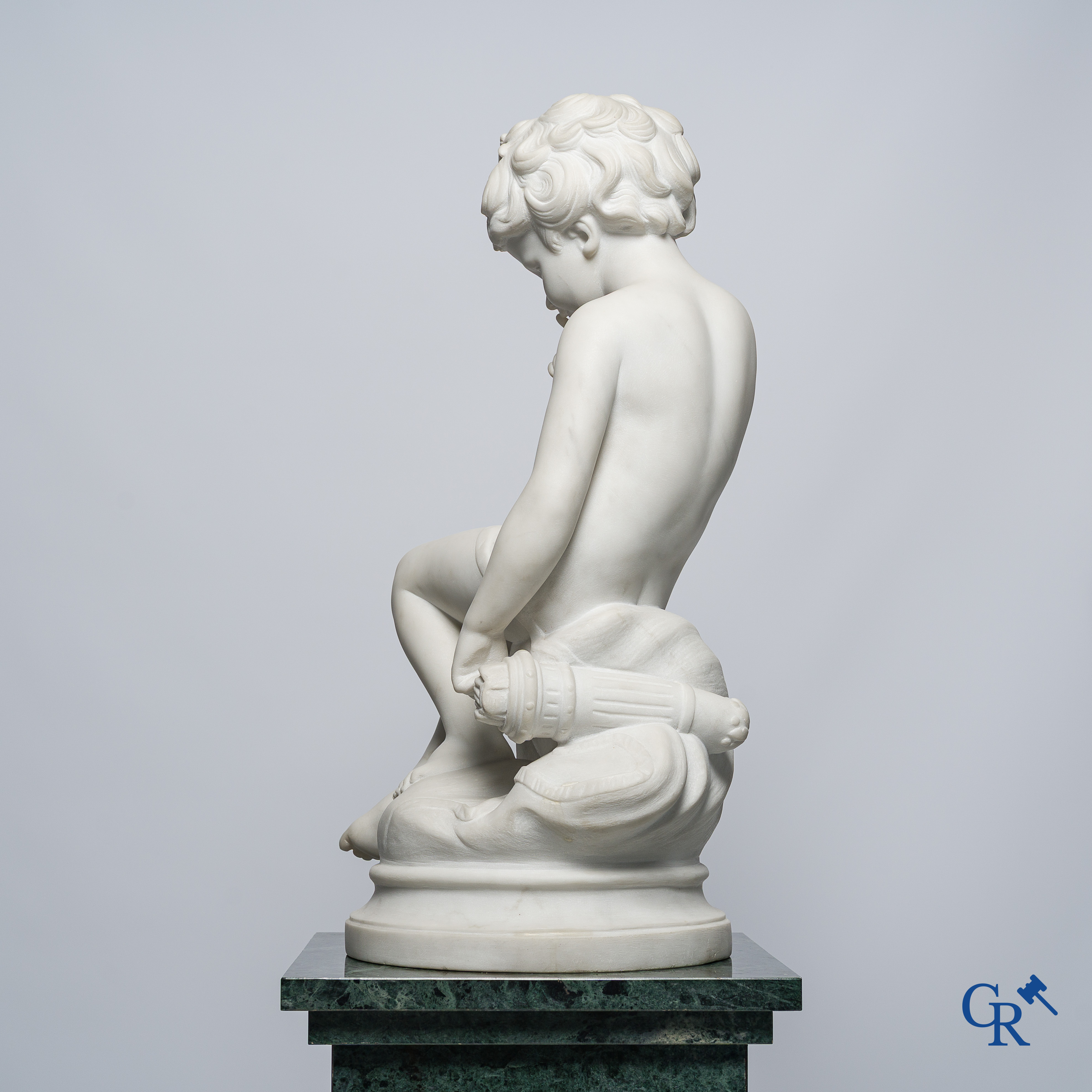 Representation of a seated cupid in white Carrara marble. In the style of Jean-Baptiste Pigalle. Around 1900..