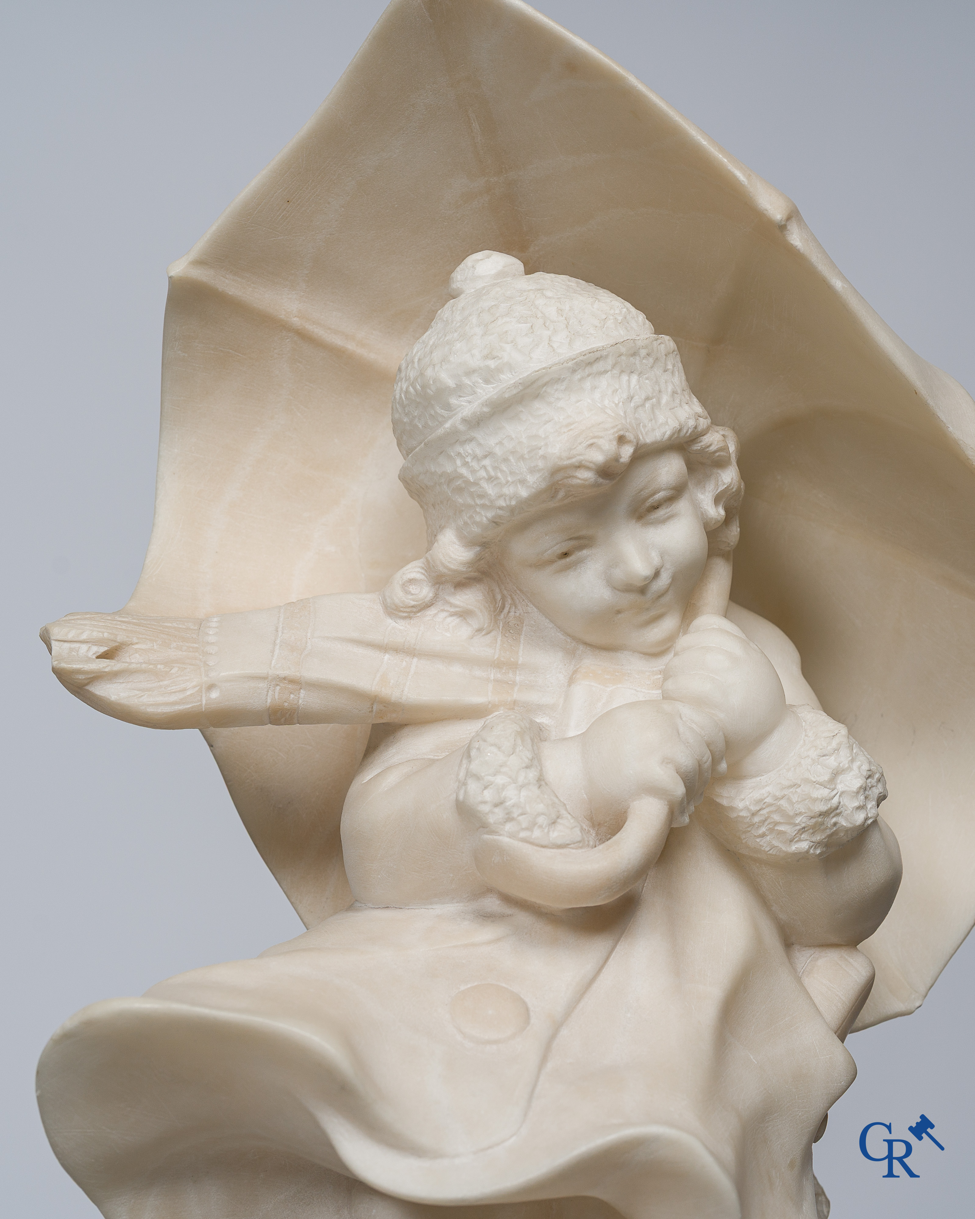 Amusing statue of a girl with umbrella in sculpted marble. No signature noticeable. Around 1920.