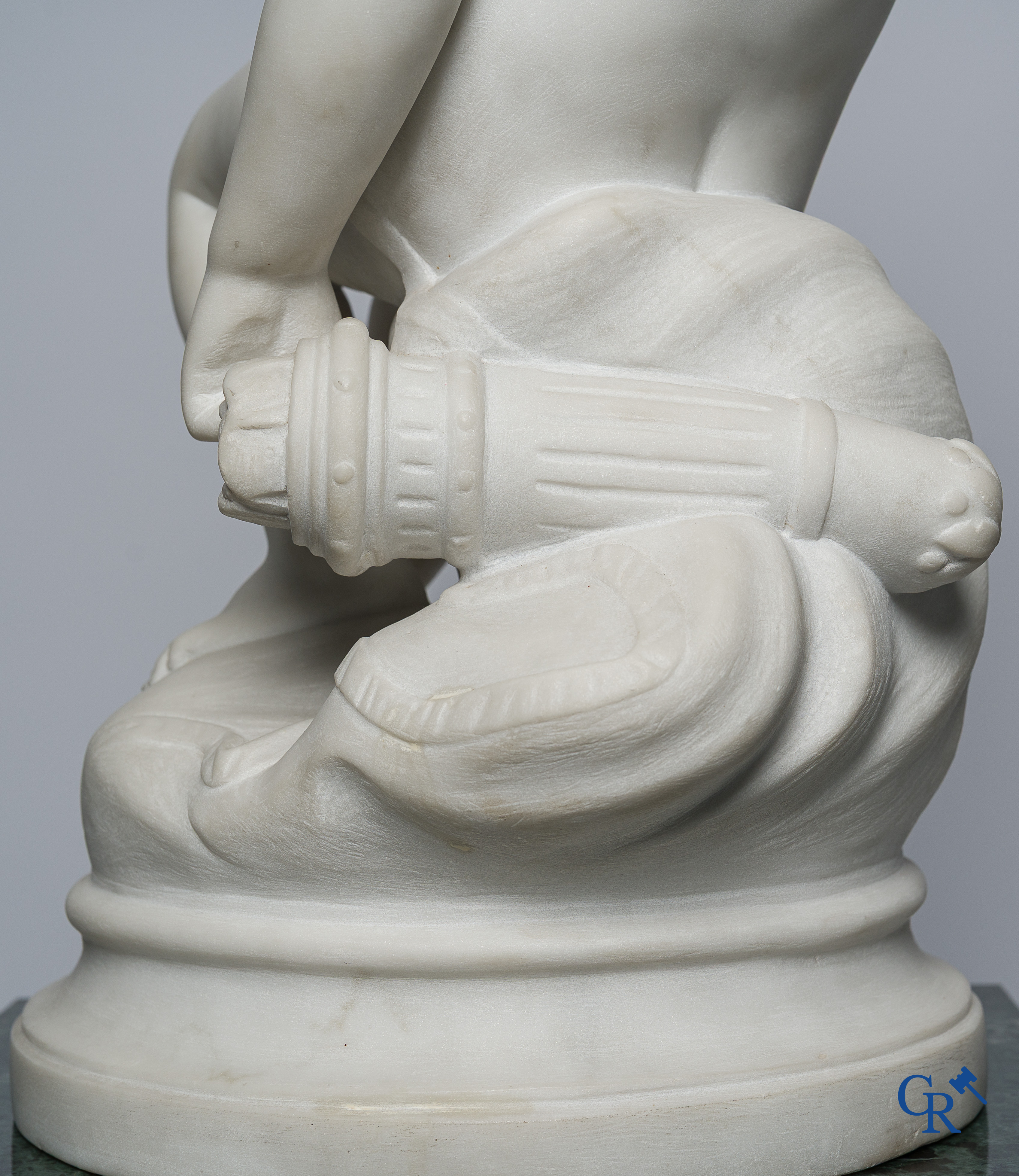Representation of a seated cupid in white Carrara marble. In the style of Jean-Baptiste Pigalle. Around 1900..