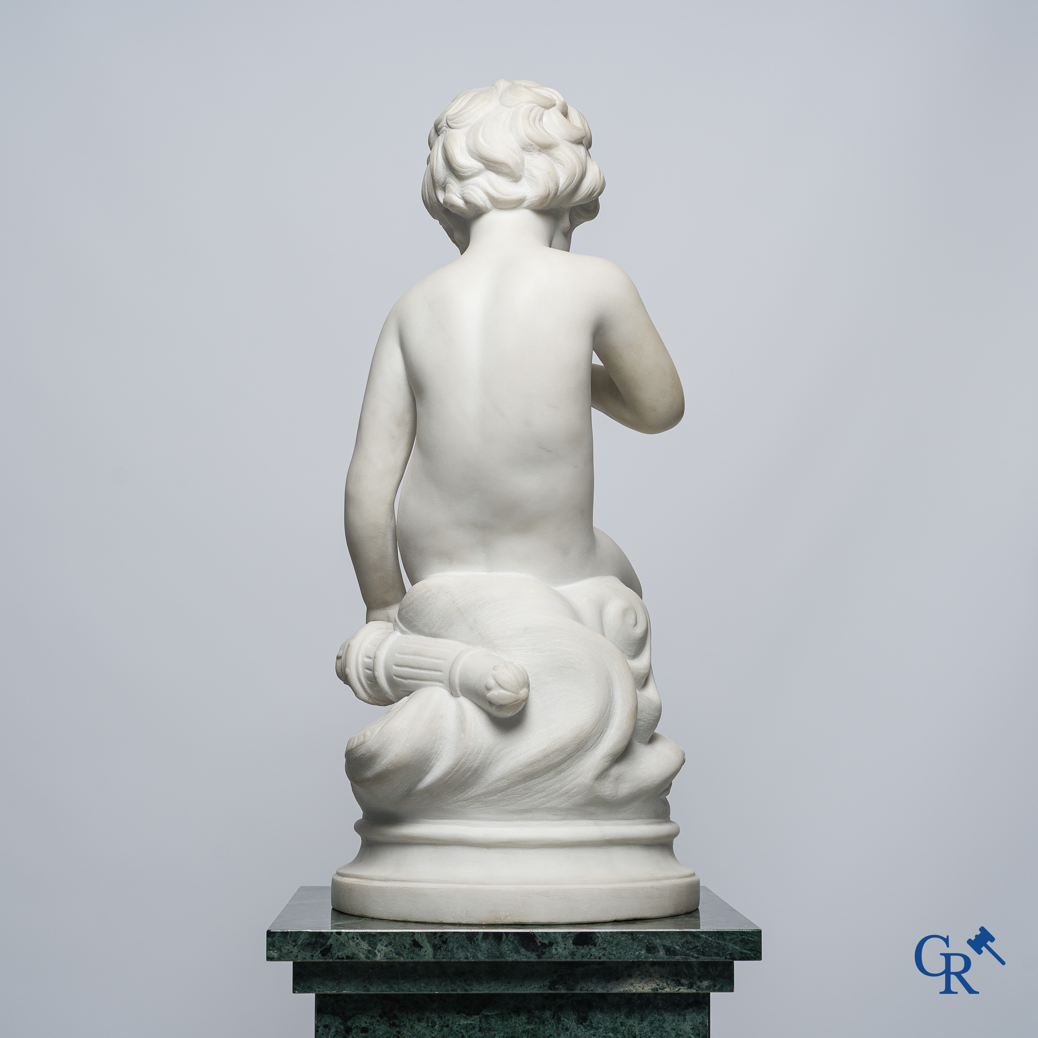 Representation of a seated cupid in white Carrara marble. In the style of Jean-Baptiste Pigalle. Around 1900..