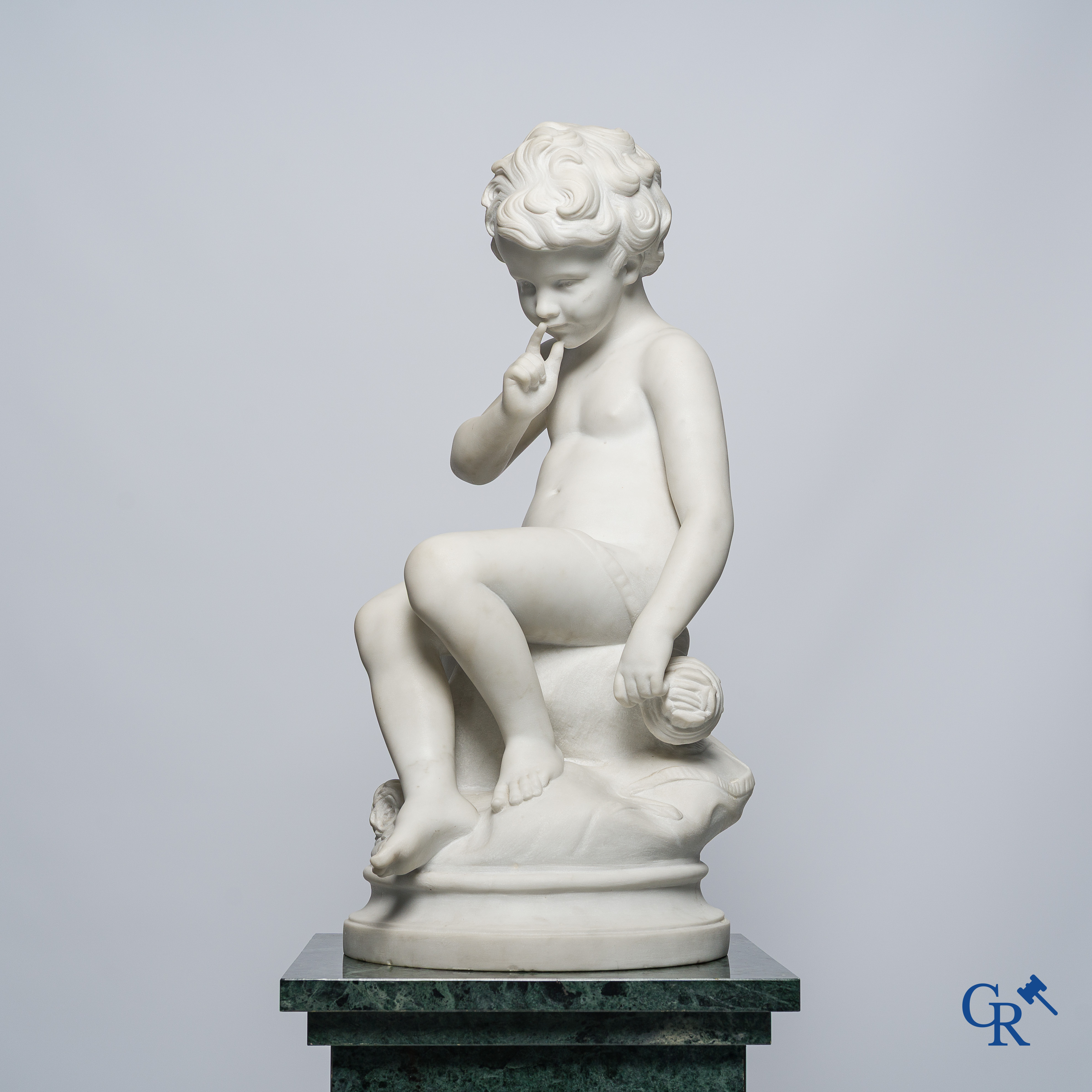 Representation of a seated cupid in white Carrara marble. In the style of Jean-Baptiste Pigalle. Around 1900..