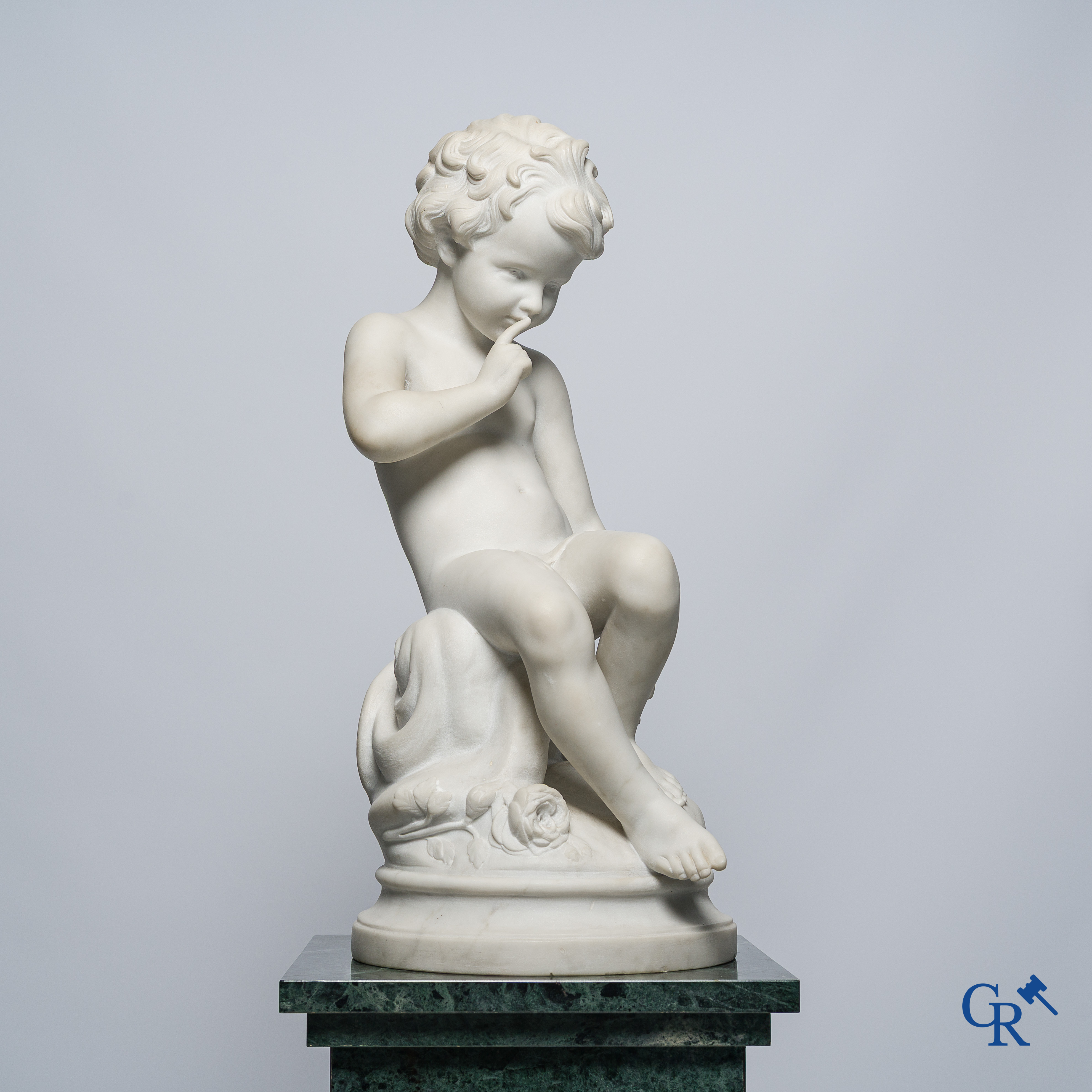 Representation of a seated cupid in white Carrara marble. In the style of Jean-Baptiste Pigalle. Around 1900..