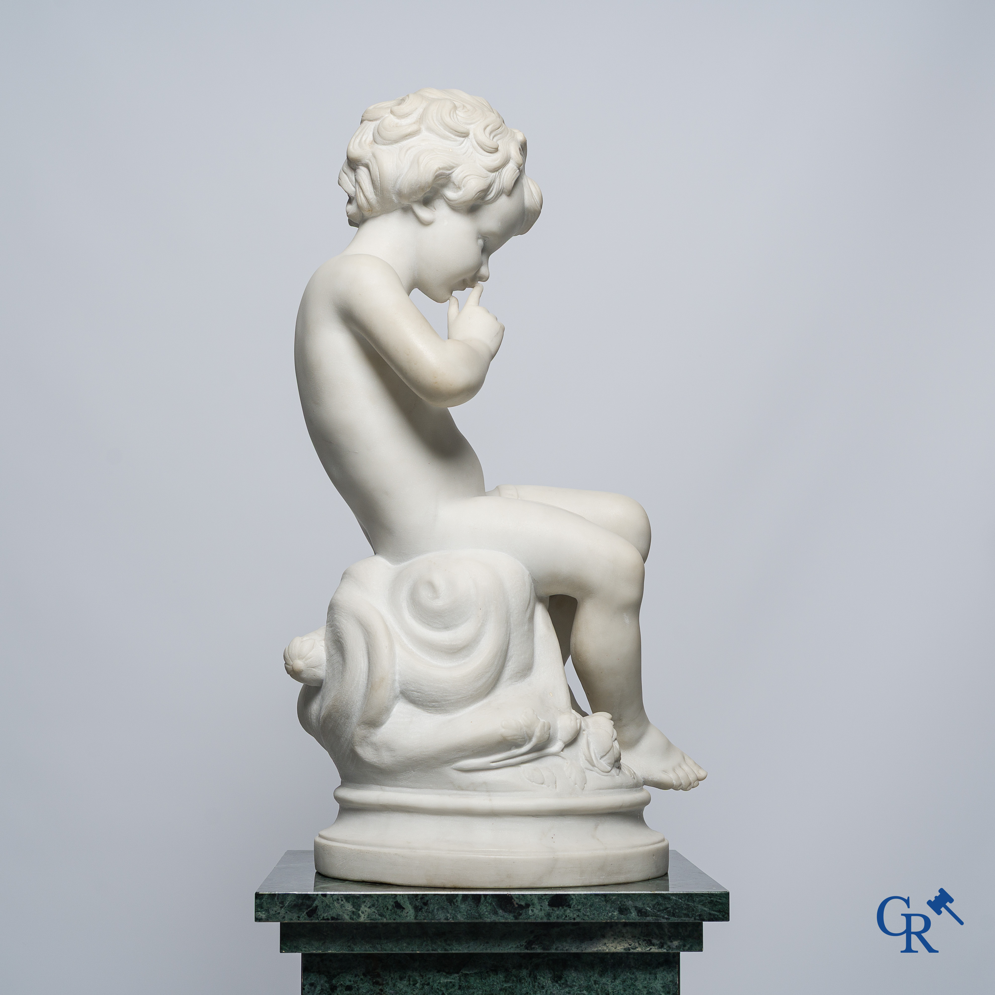Representation of a seated cupid in white Carrara marble. In the style of Jean-Baptiste Pigalle. Around 1900..