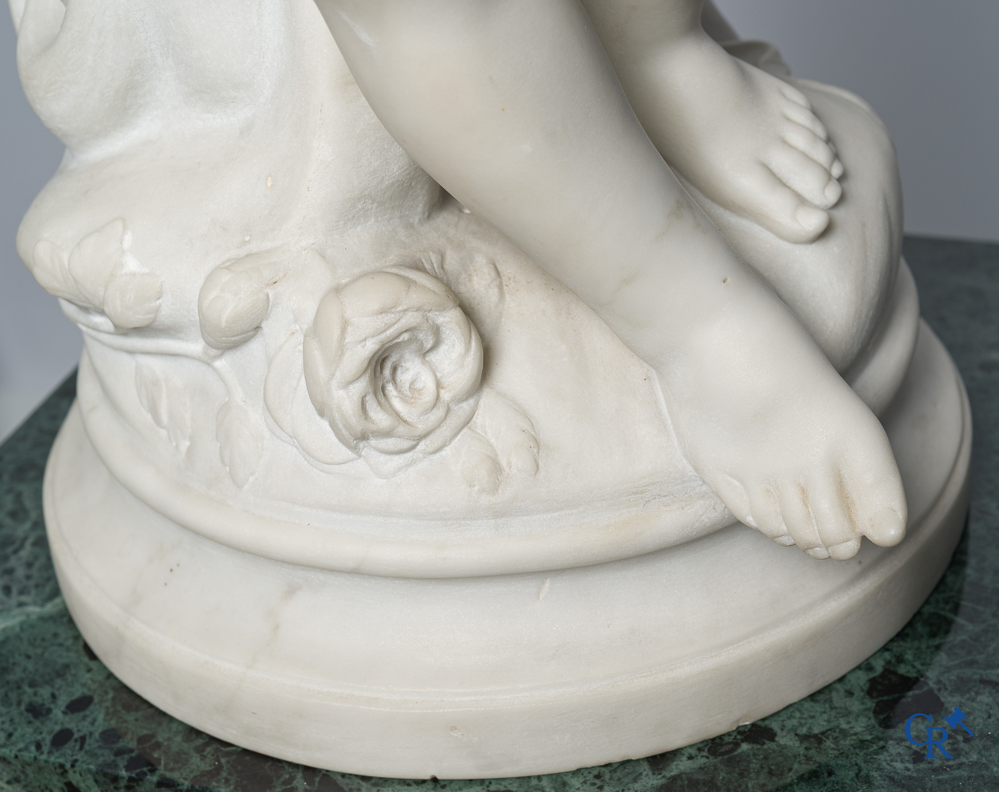 Representation of a seated cupid in white Carrara marble. In the style of Jean-Baptiste Pigalle. Around 1900..