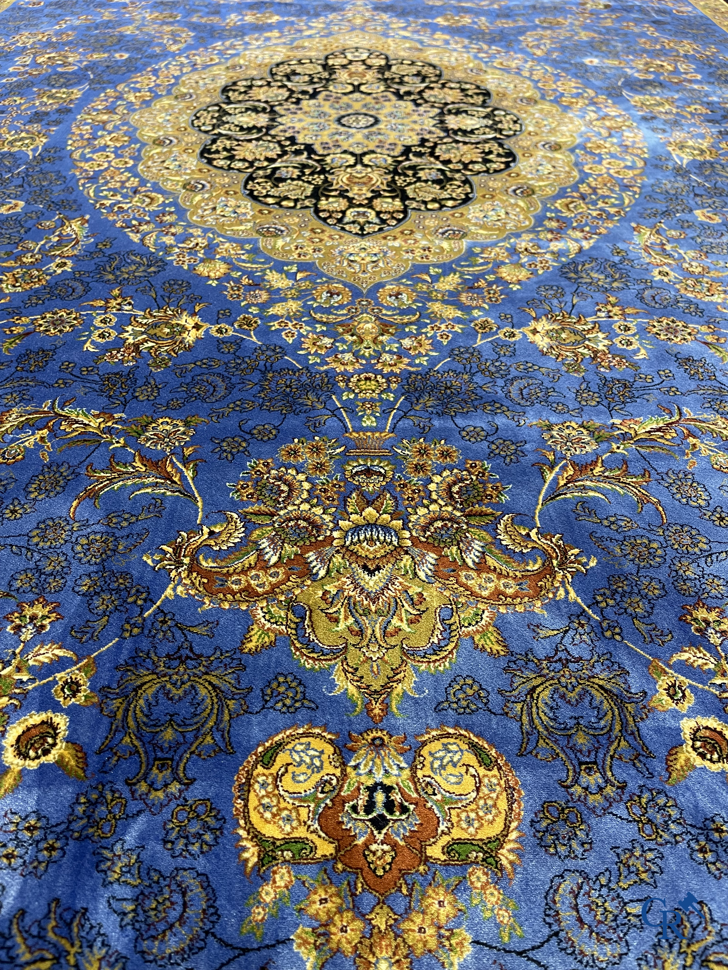 Tapis. Exceptionnel tapis en soie avec un décor floral sur fond bleu.