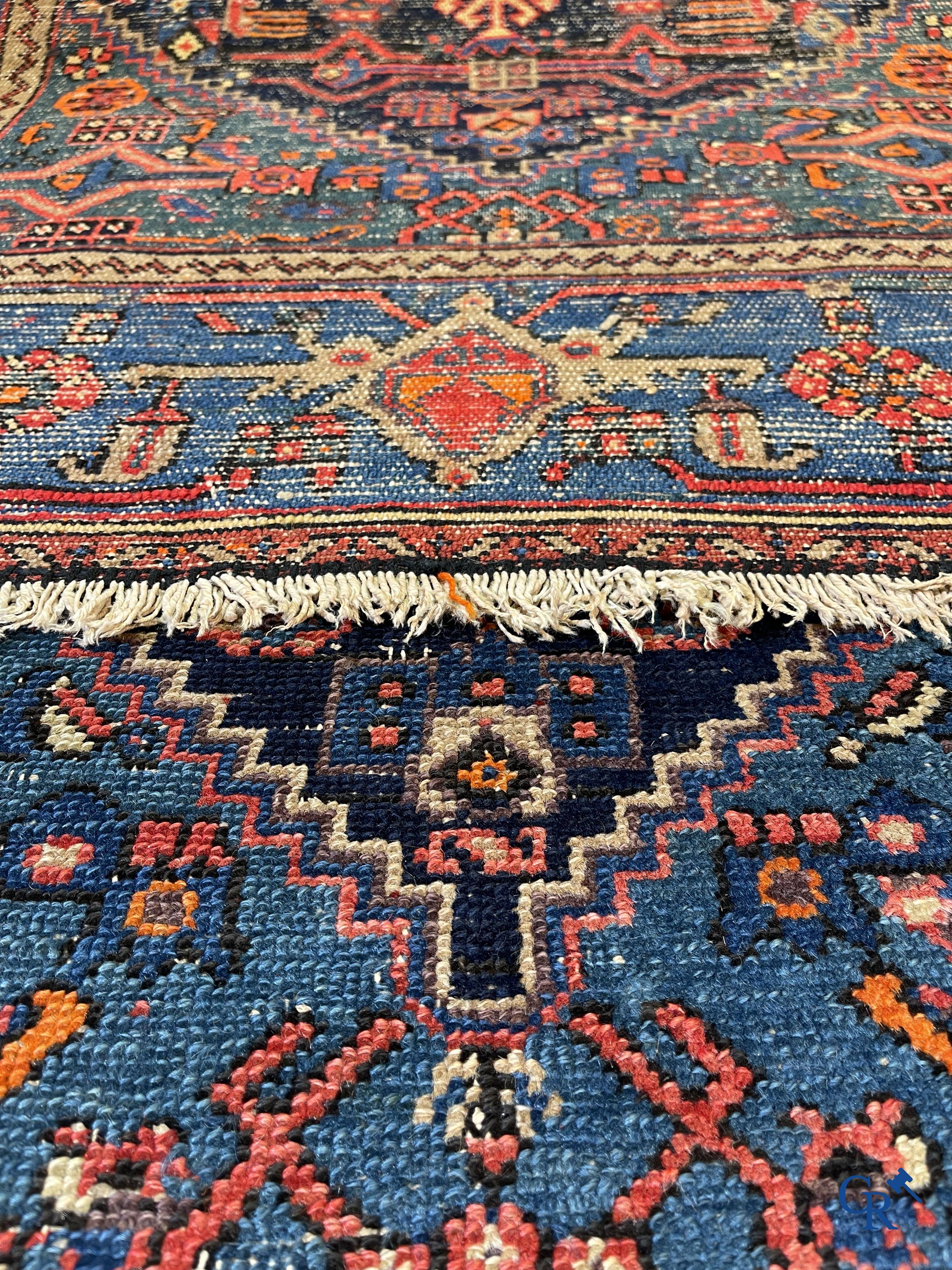 Antique Oriental carpets, an antique hand-knotted carpet with motifs on a blue background.