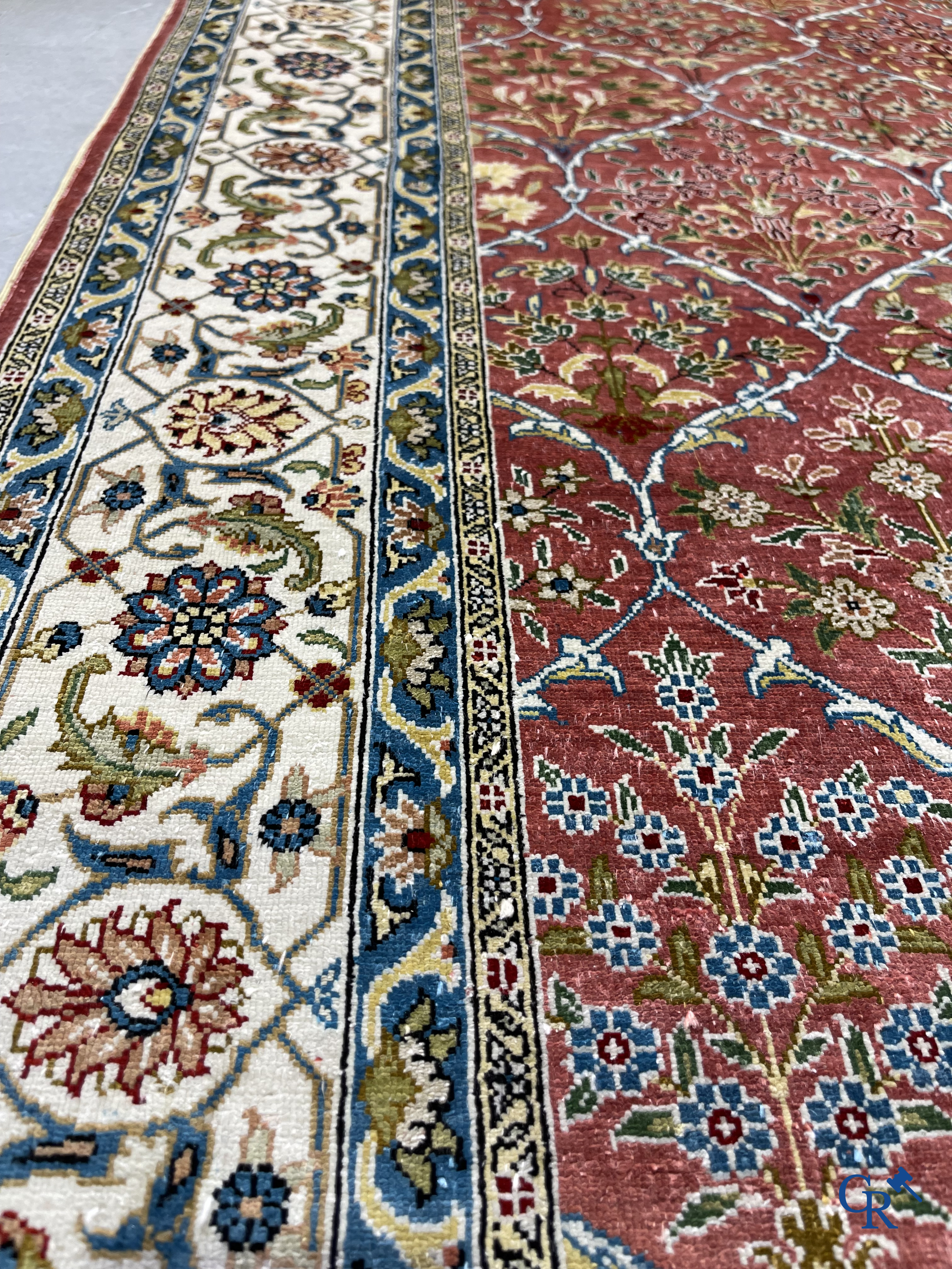 Tapis d'Orient: Un tapis finement noué à la main en laine et soie avec un décor floral.<br />
Signé.