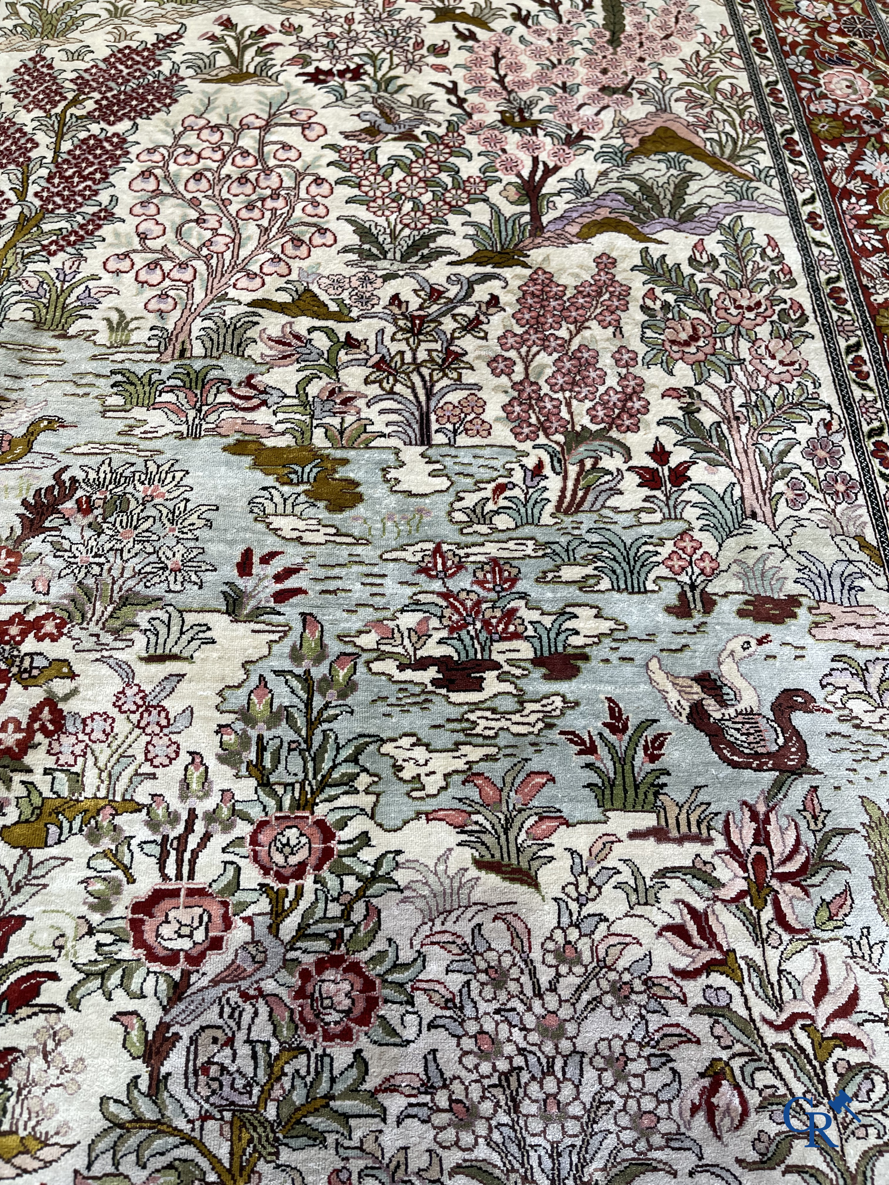 Tapis d'Orient: Un tapis en soie finement noué à la main avec des oiseaux aquatiques dans un paysage sur fond floral.