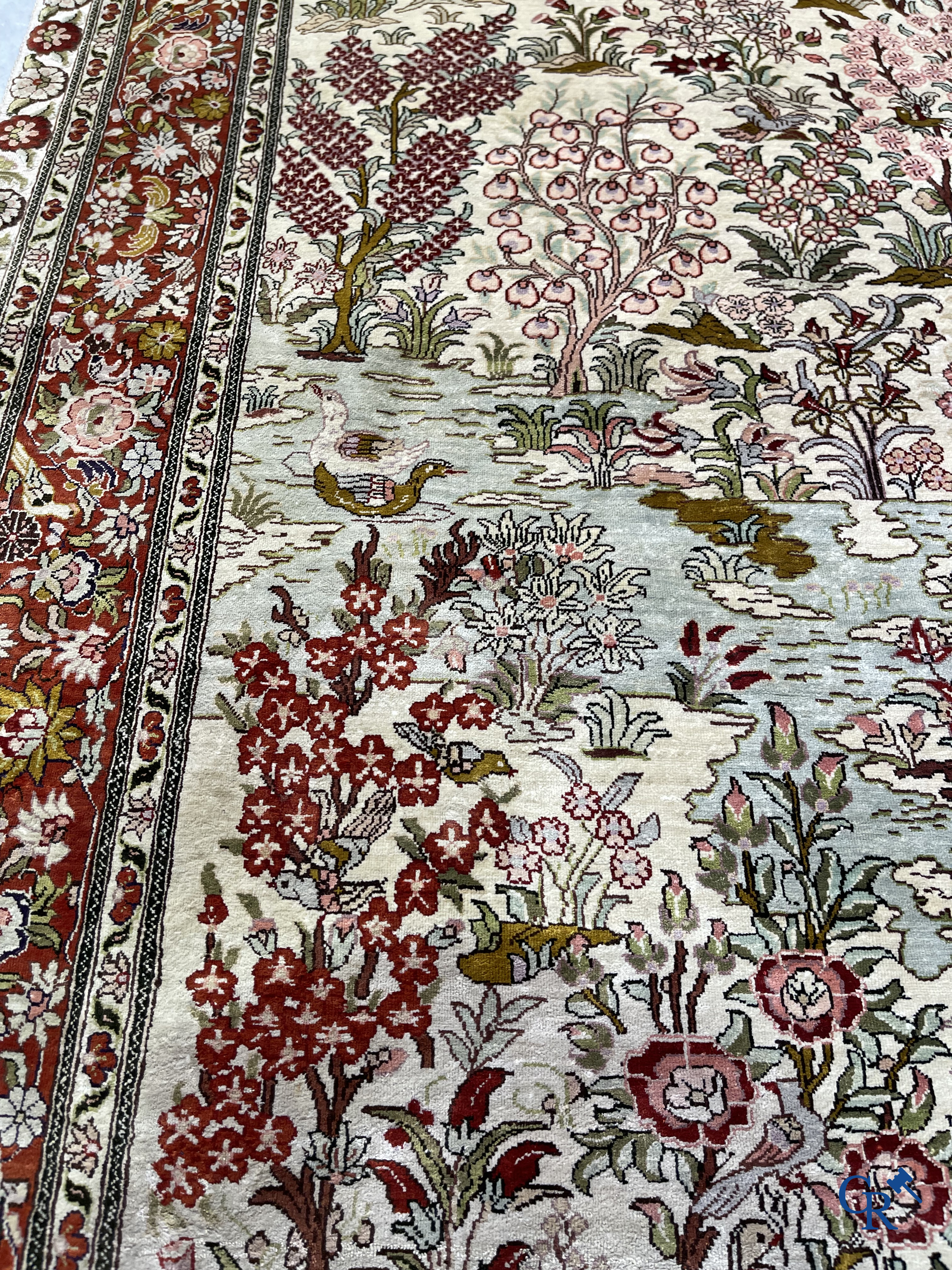 Tapis d'Orient: Un tapis en soie finement noué à la main avec des oiseaux aquatiques dans un paysage sur fond floral.