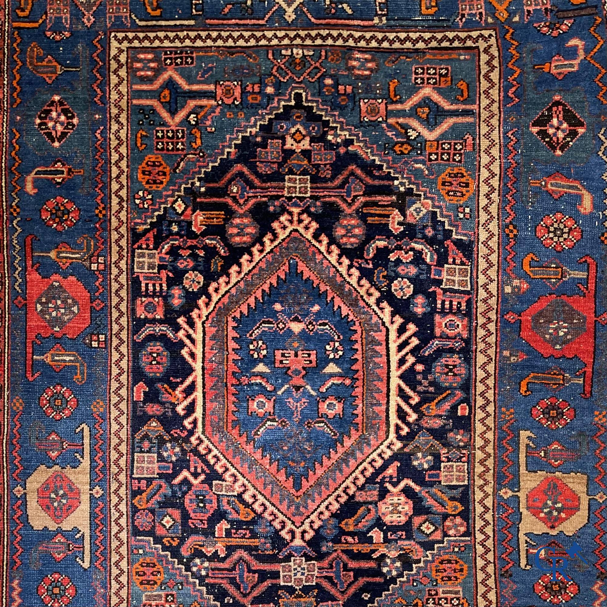 Antique Oriental carpets, an antique hand-knotted carpet with motifs on a blue background.