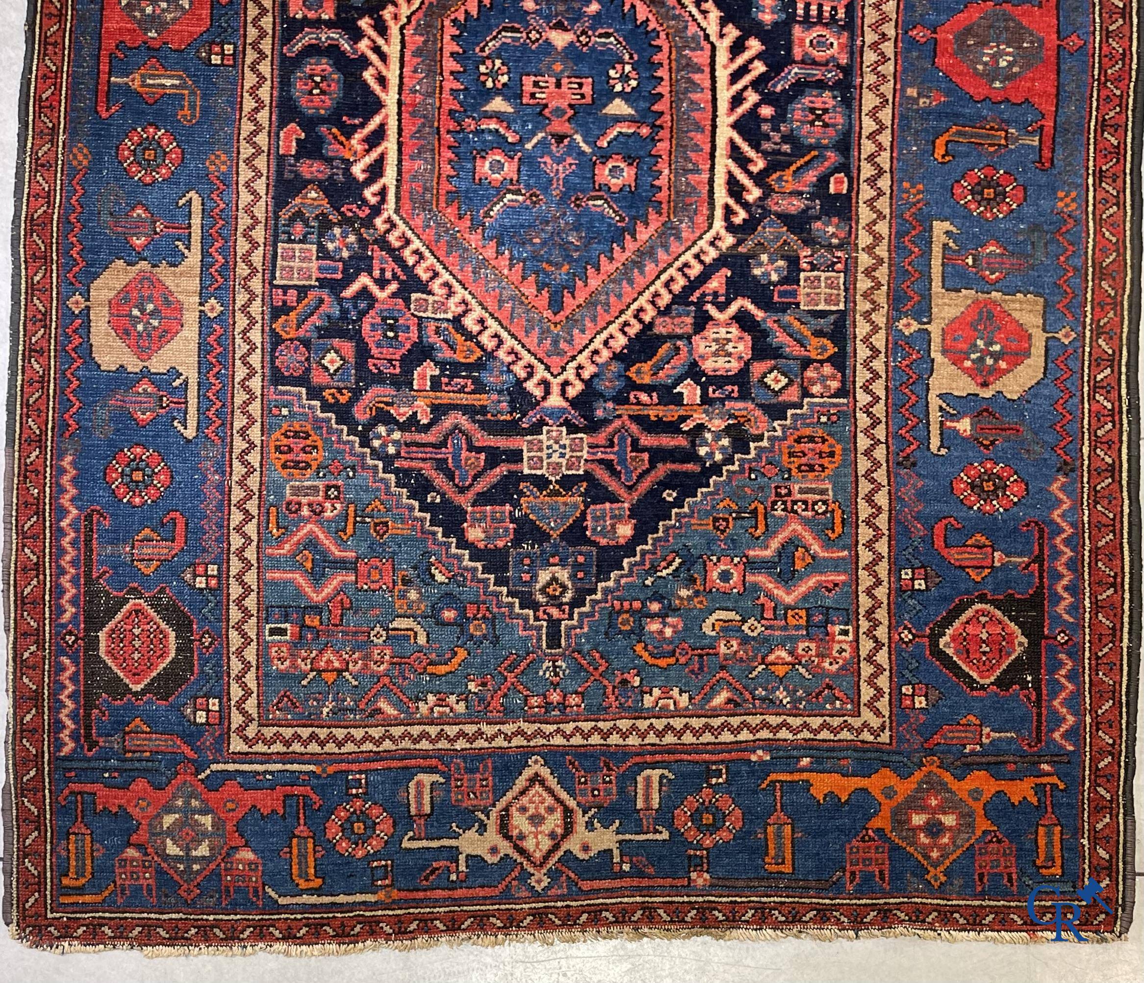 Antique Oriental carpets, an antique hand-knotted carpet with motifs on a blue background.