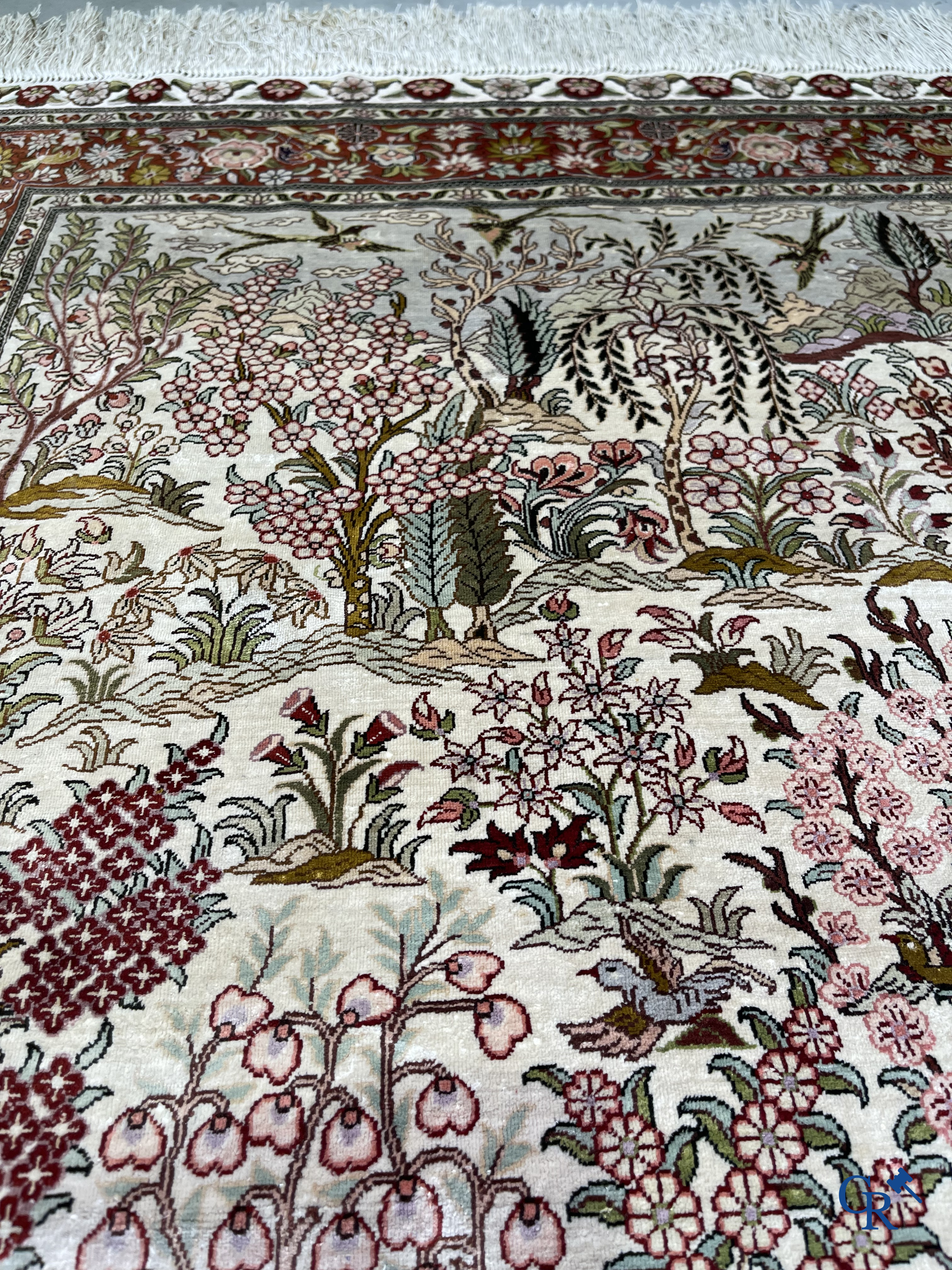 Tapis d'Orient: Un tapis en soie finement noué à la main avec des oiseaux aquatiques dans un paysage sur fond floral.