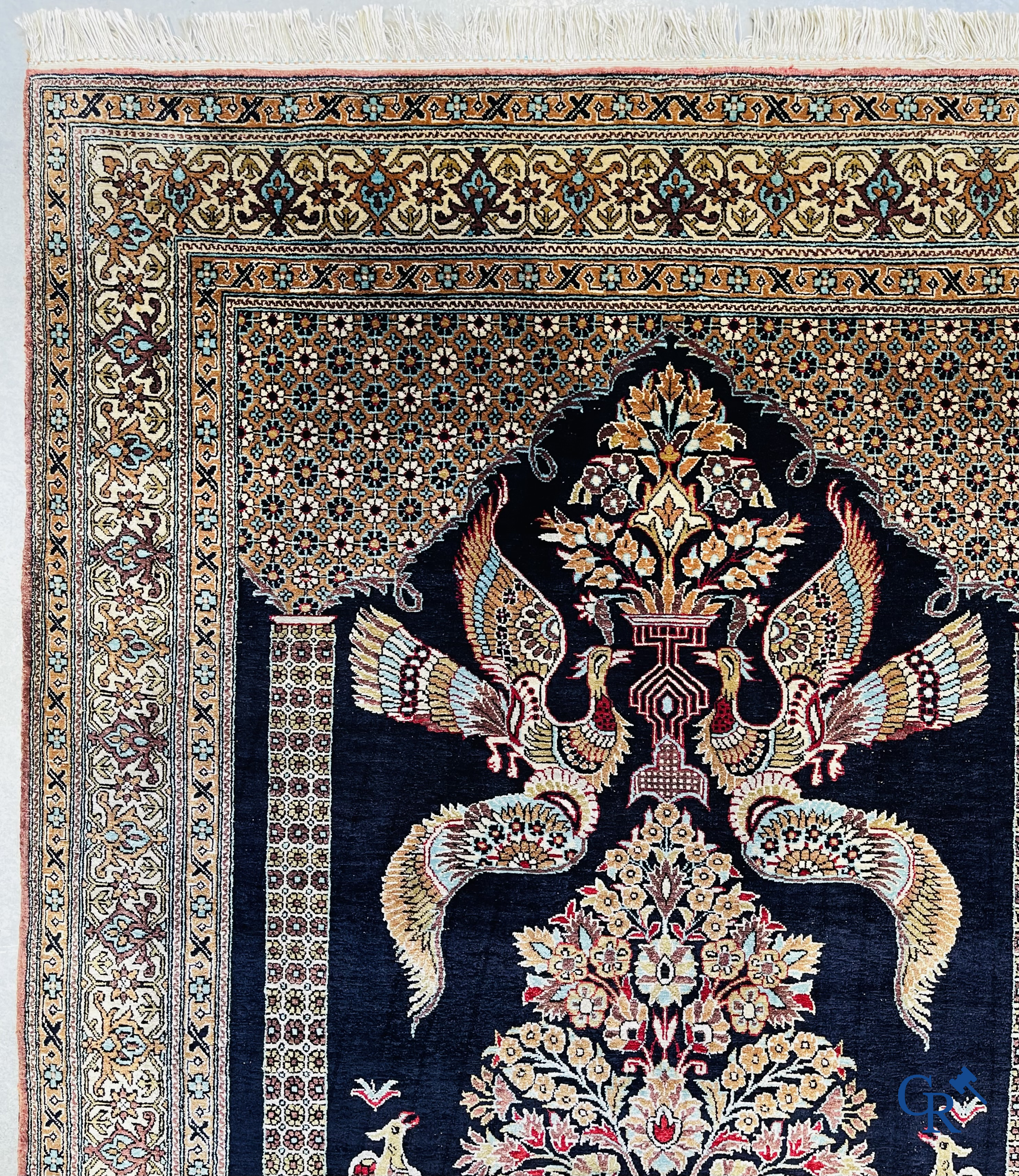 Persian carpets: A finely knotted silk Ghoum carpet with a decor of birds and flowers.