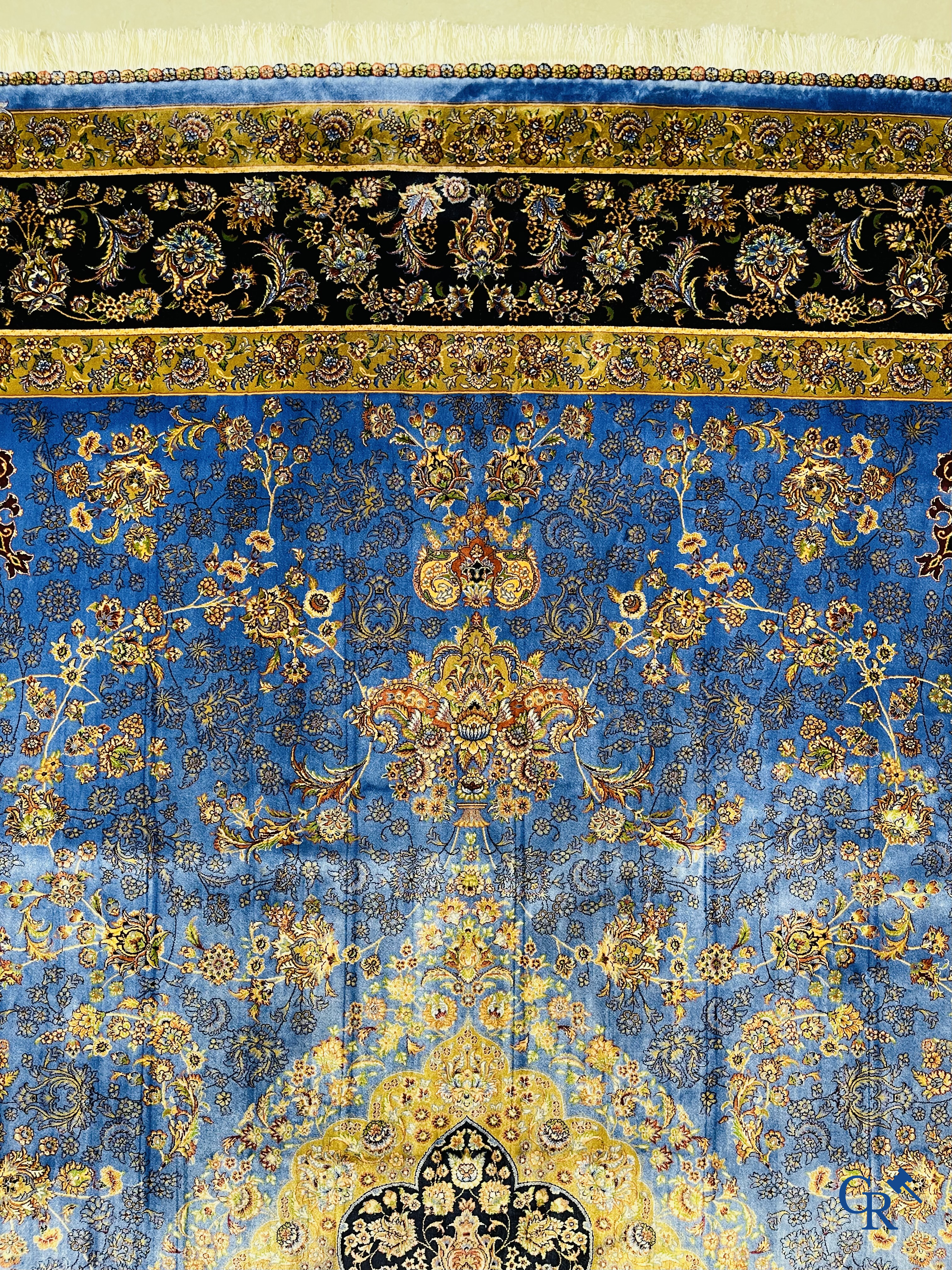 Tapis. Exceptionnel tapis en soie avec un décor floral sur fond bleu.