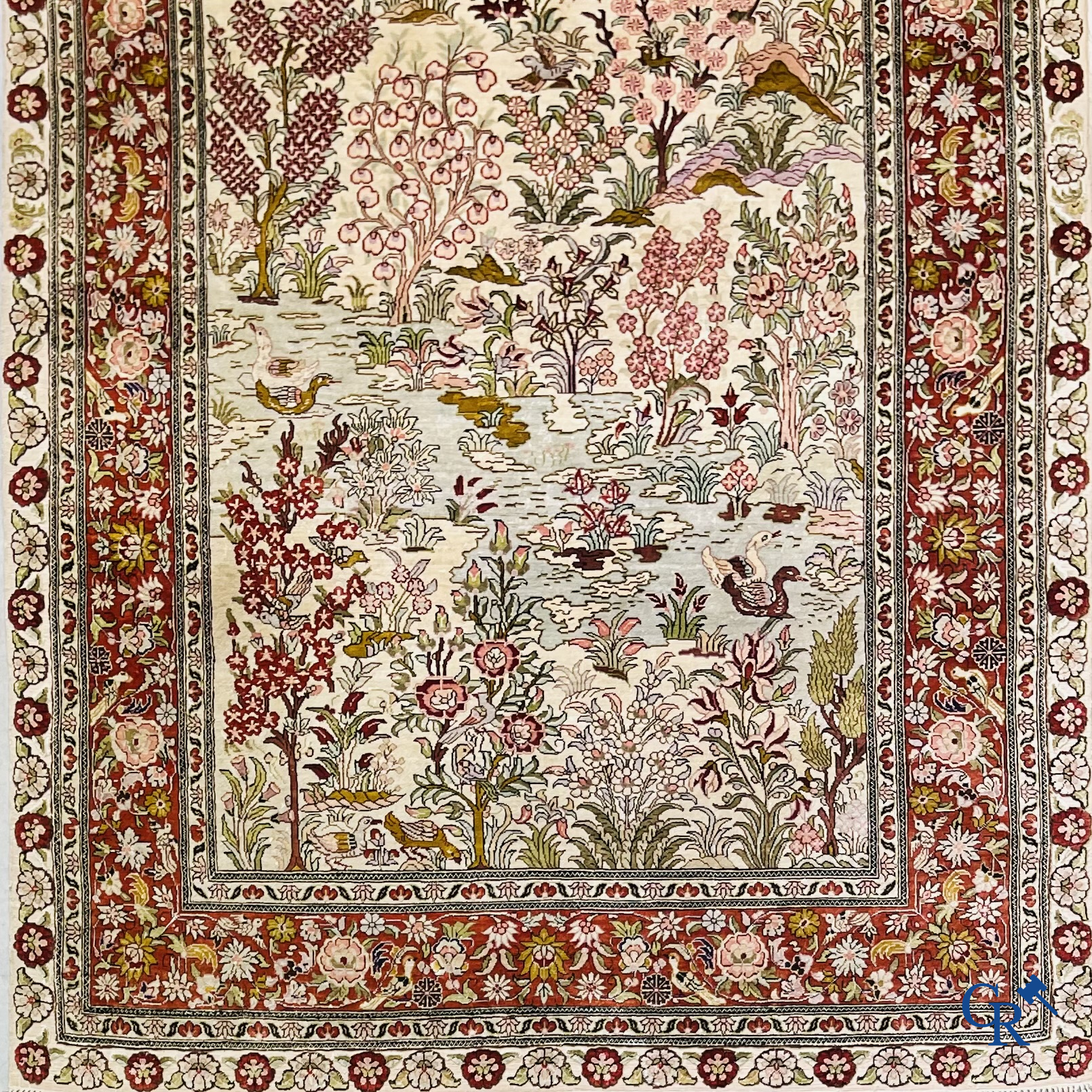 Tapis d'Orient: Un tapis en soie finement noué à la main avec des oiseaux aquatiques dans un paysage sur fond floral.