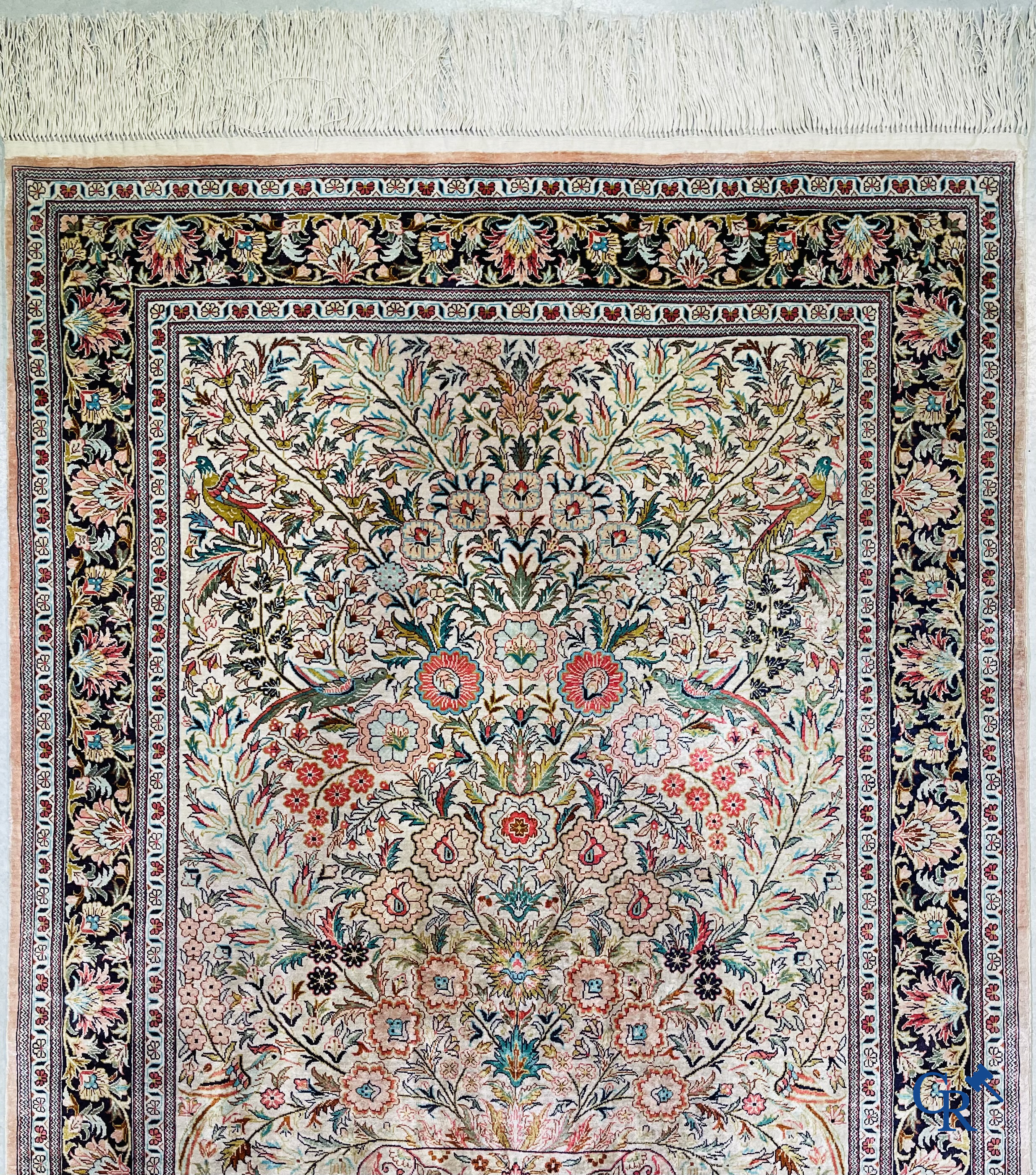 Tapis d'Orient: Un tapis persan en soie finement noué à la main avec un vase à fleurs et des oiseaux dans un décor floral.