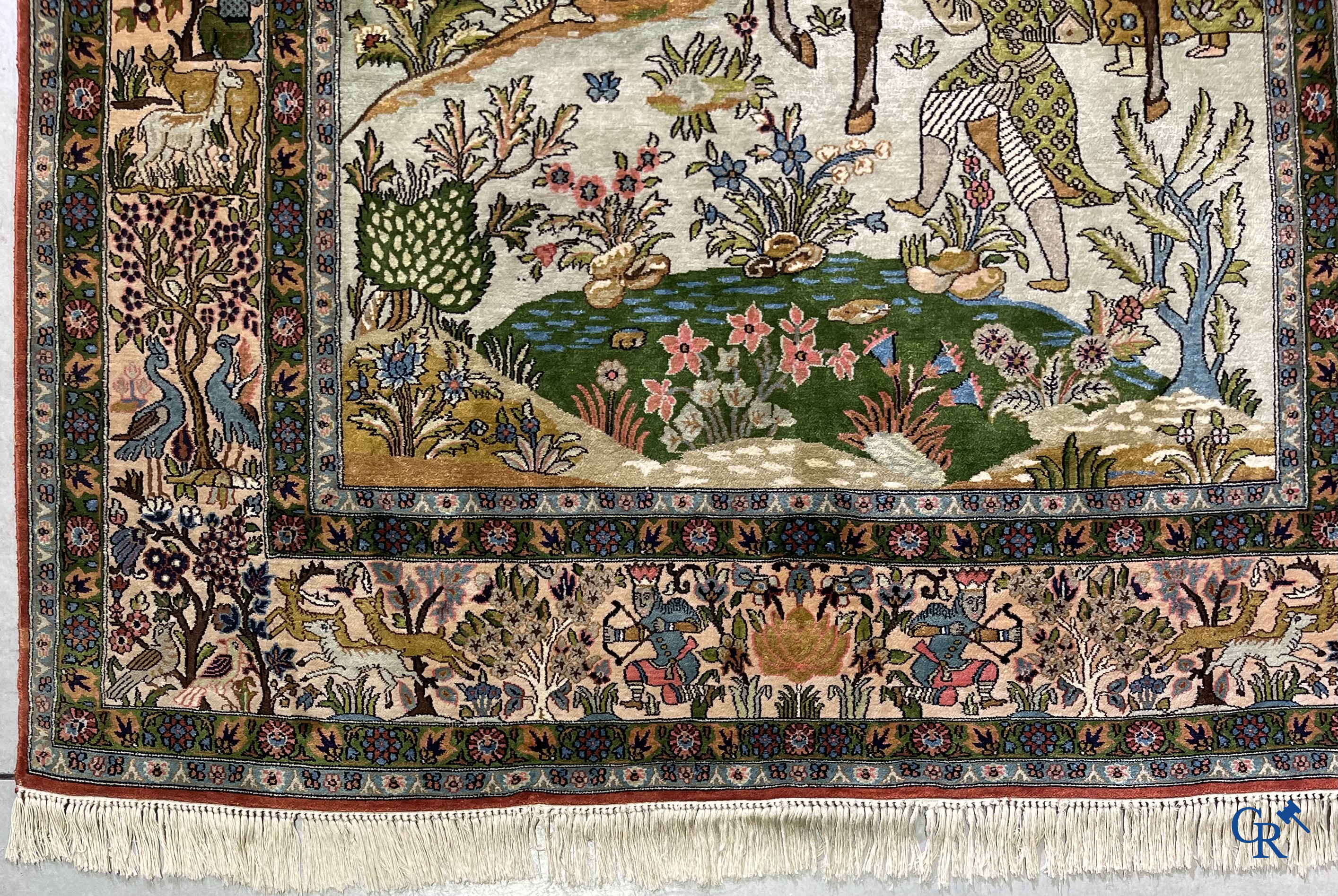 Tapis d'Orient. Iran. Un tapis persan en soie finement noué à la main avec des personnages et un cheval dans un paysage.