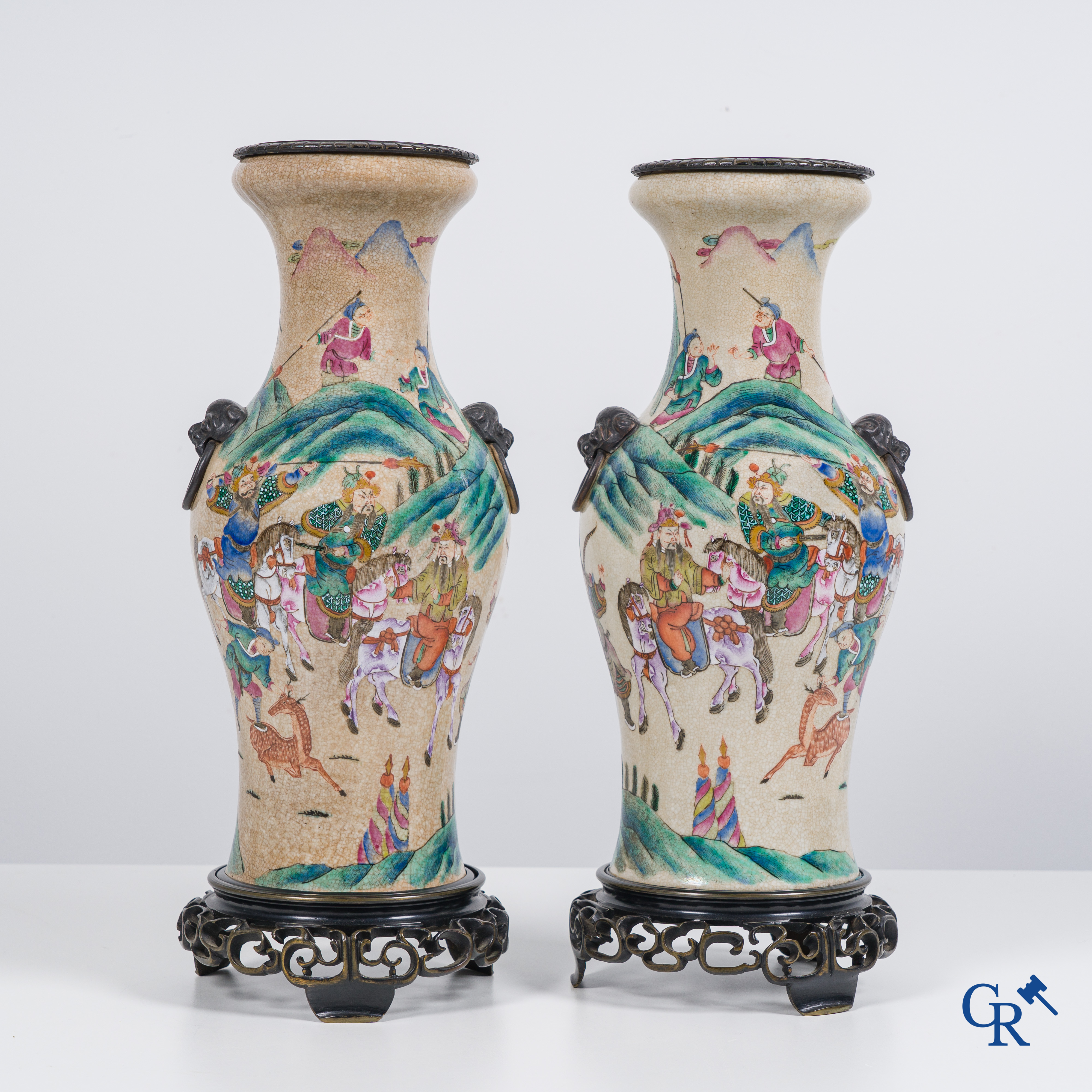 Asian Art: Chinese porcelain. A pair of finely decorated famille rose vases in a bronze frame. 19th century.