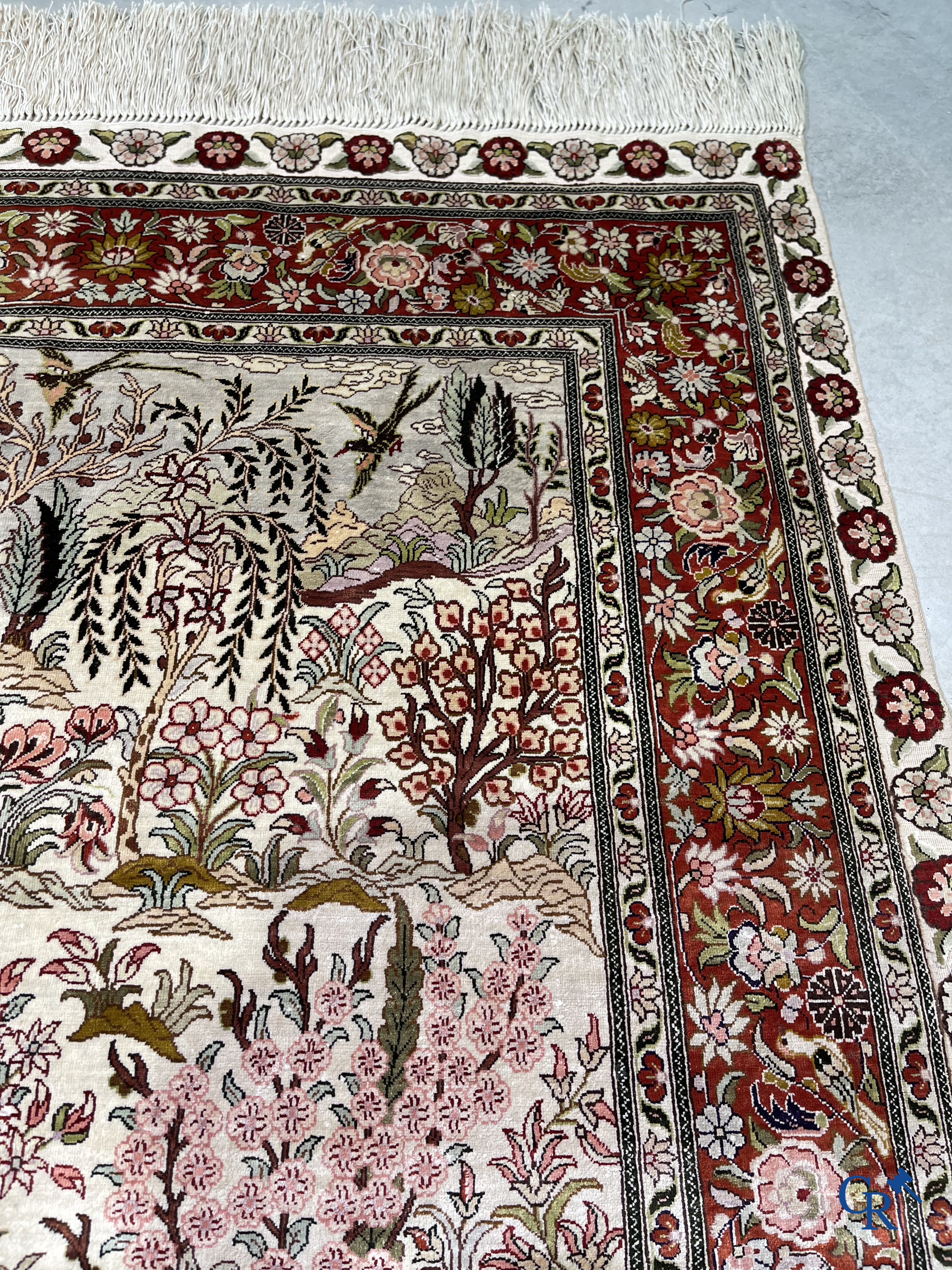 Tapis d'Orient: Un tapis en soie finement noué à la main avec des oiseaux aquatiques dans un paysage sur fond floral.