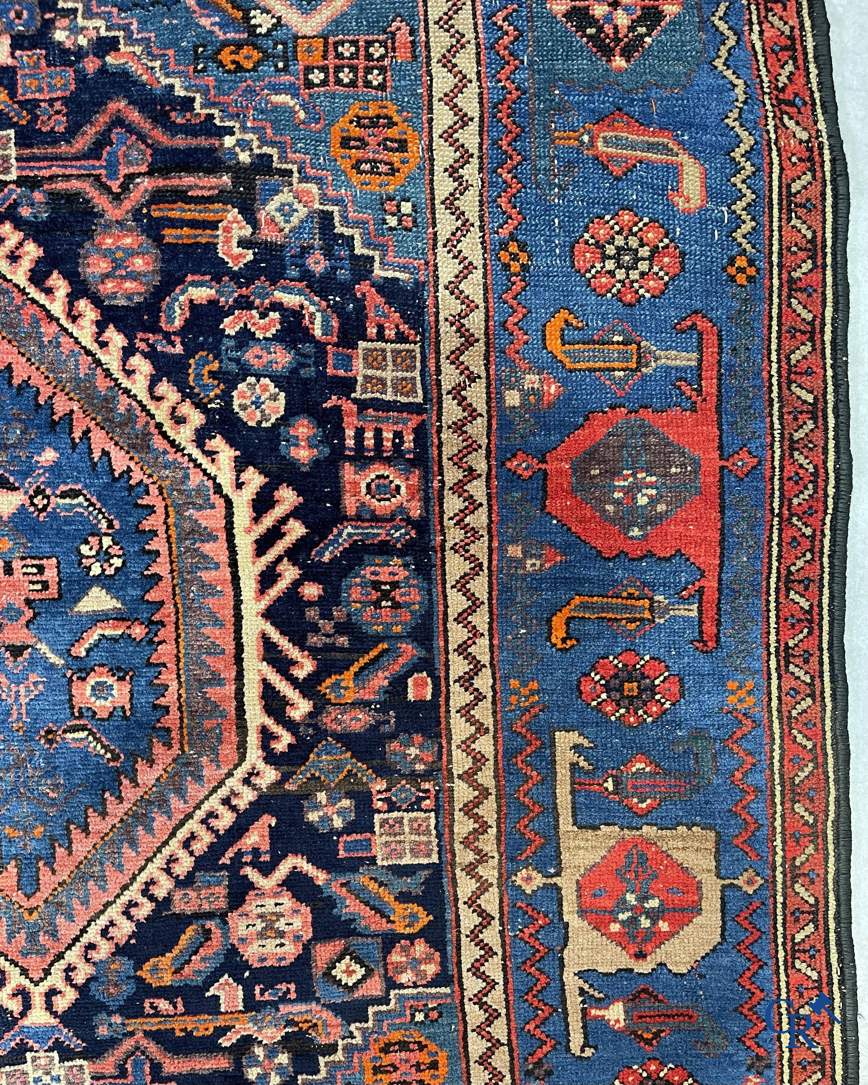 Antique Oriental carpets, an antique hand-knotted carpet with motifs on a blue background.