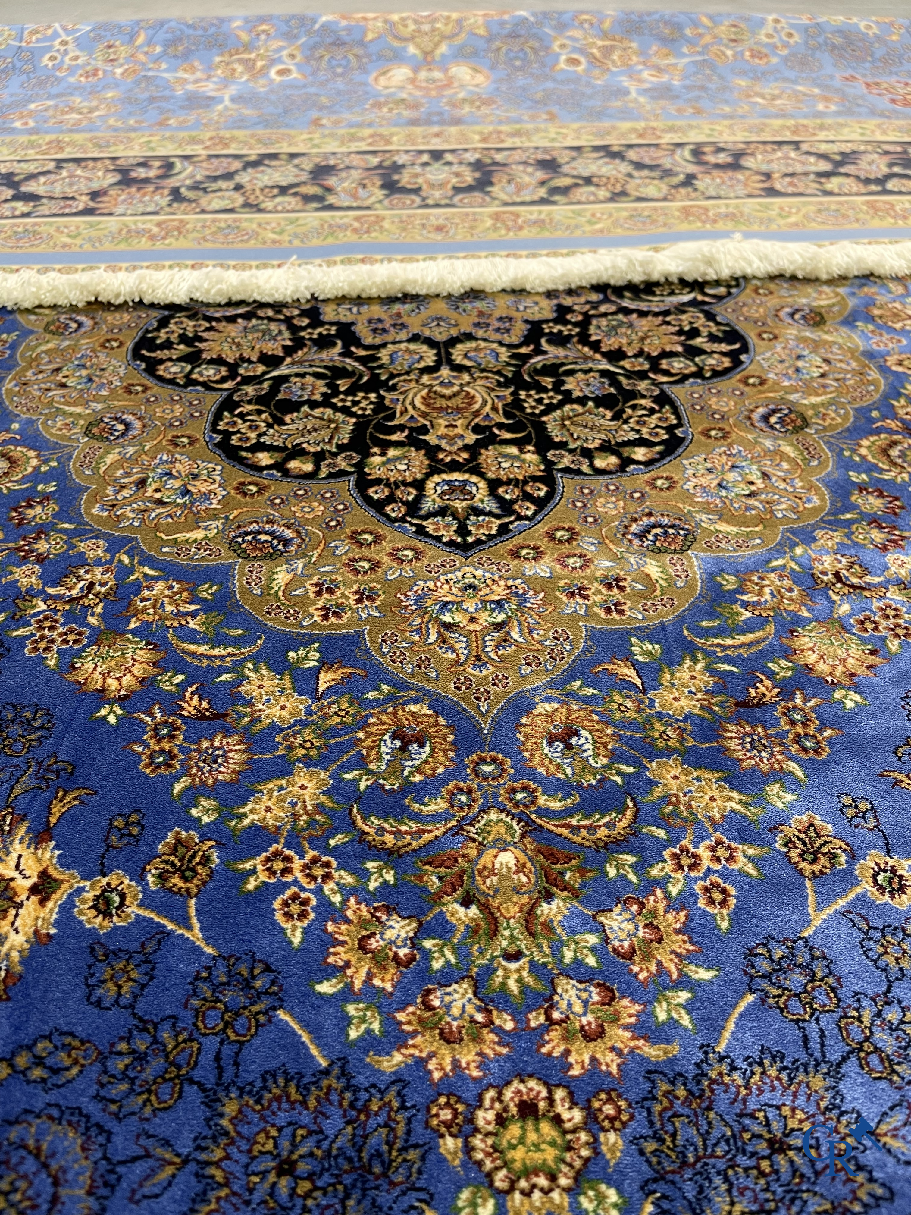 Tapis. Exceptionnel tapis en soie avec un décor floral sur fond bleu.