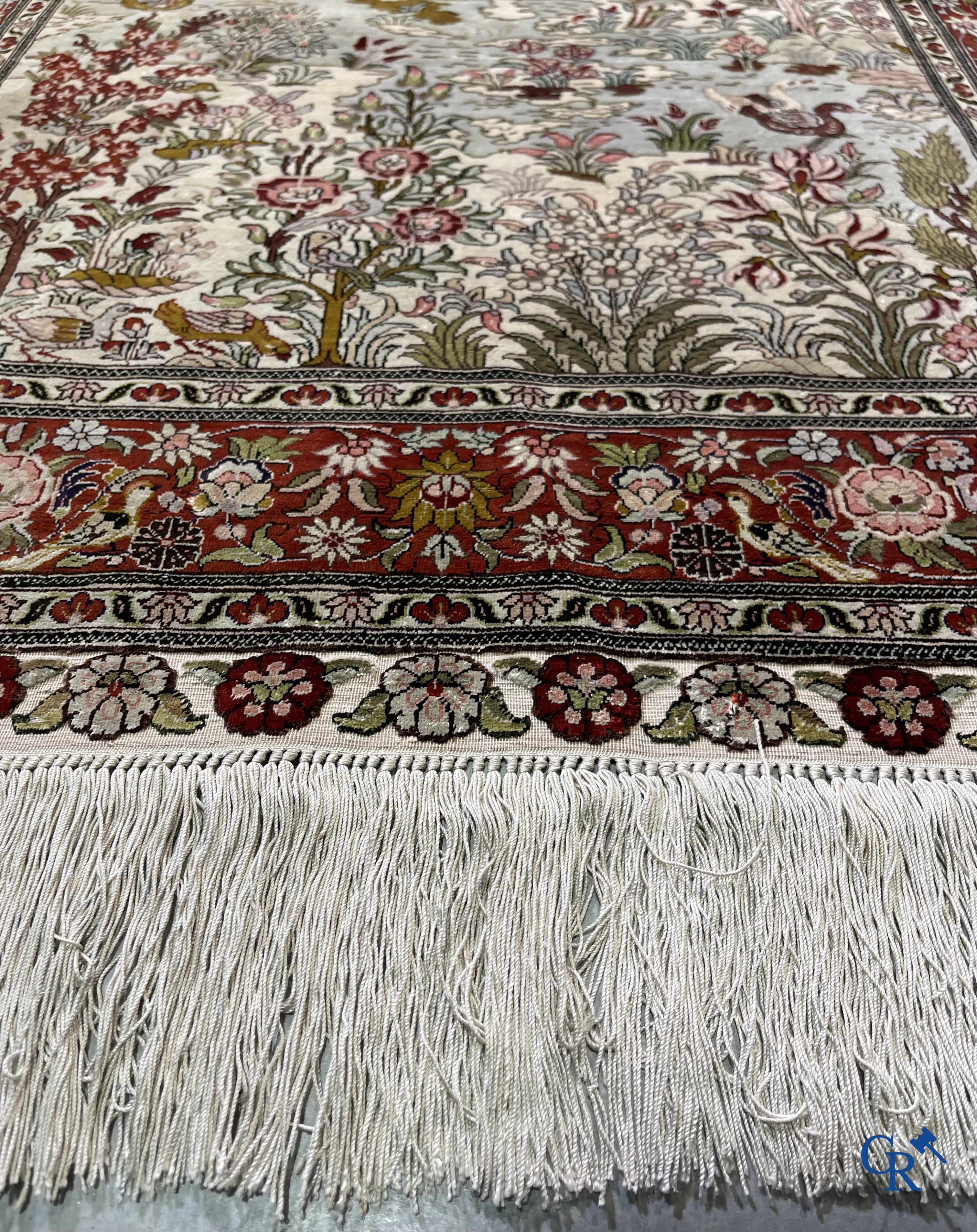 Tapis d'Orient: Un tapis en soie finement noué à la main avec des oiseaux aquatiques dans un paysage sur fond floral.