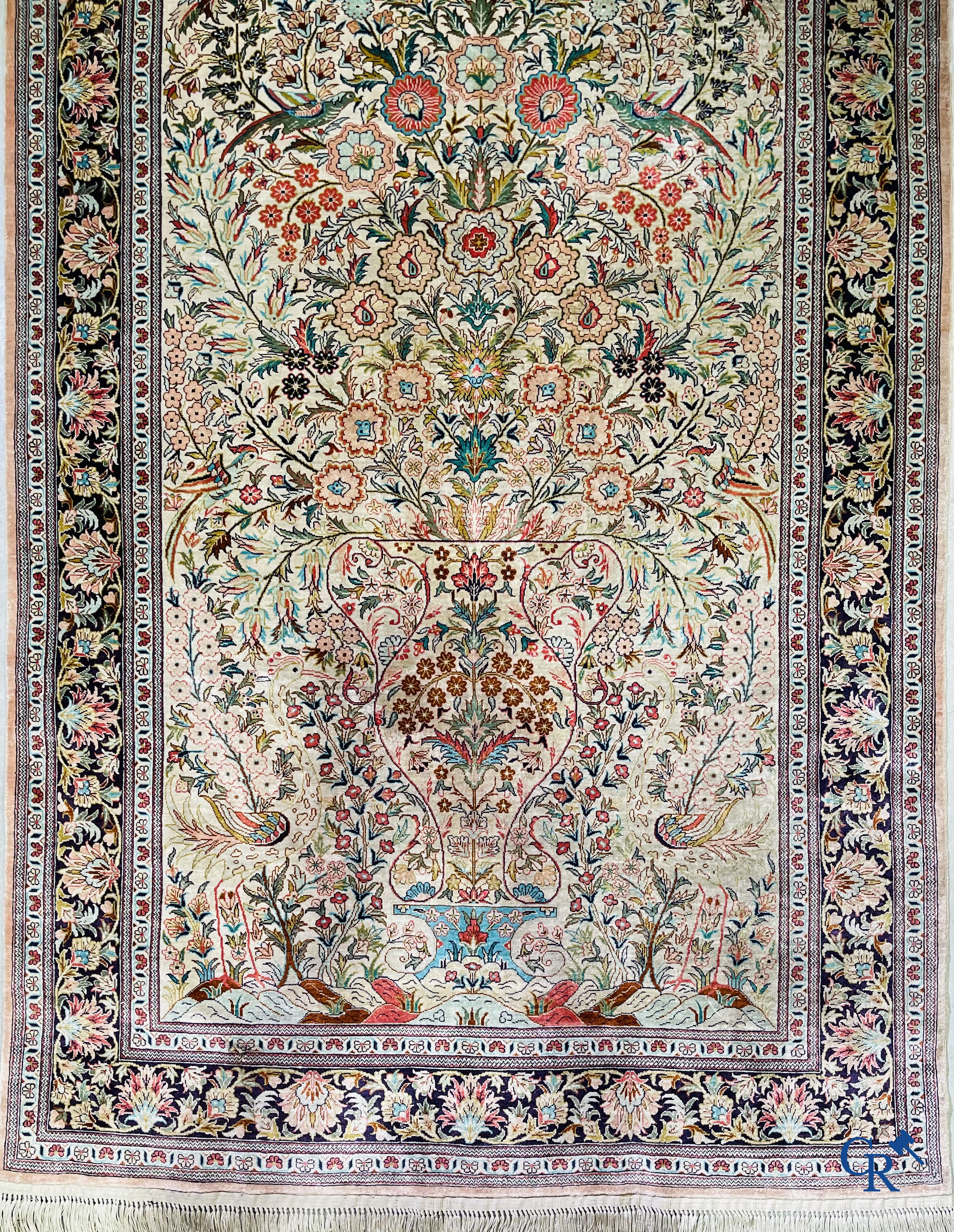 Tapis d'Orient: Un tapis persan en soie finement noué à la main avec un vase à fleurs et des oiseaux dans un décor floral.