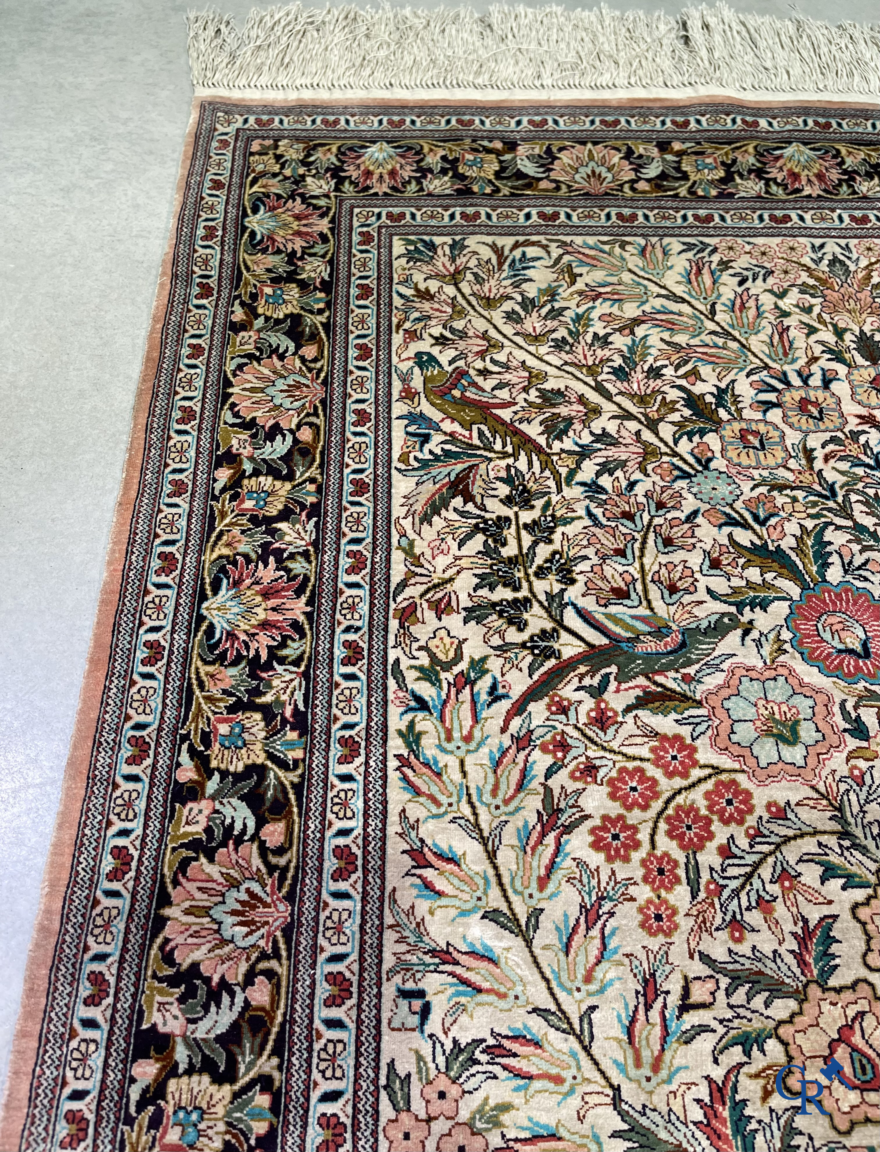 Tapis d'Orient: Un tapis persan en soie finement noué à la main avec un vase à fleurs et des oiseaux dans un décor floral.