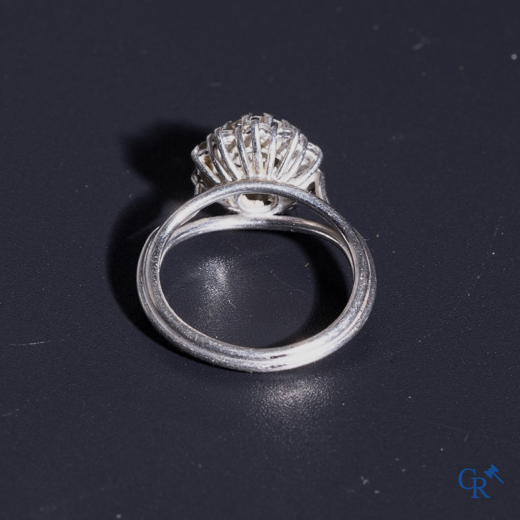 Juwelen: Een damesring in witgoud 18K (750°/00) met een centrale diamant van 0,5 ct omringd door 10 kleine diamantjes.