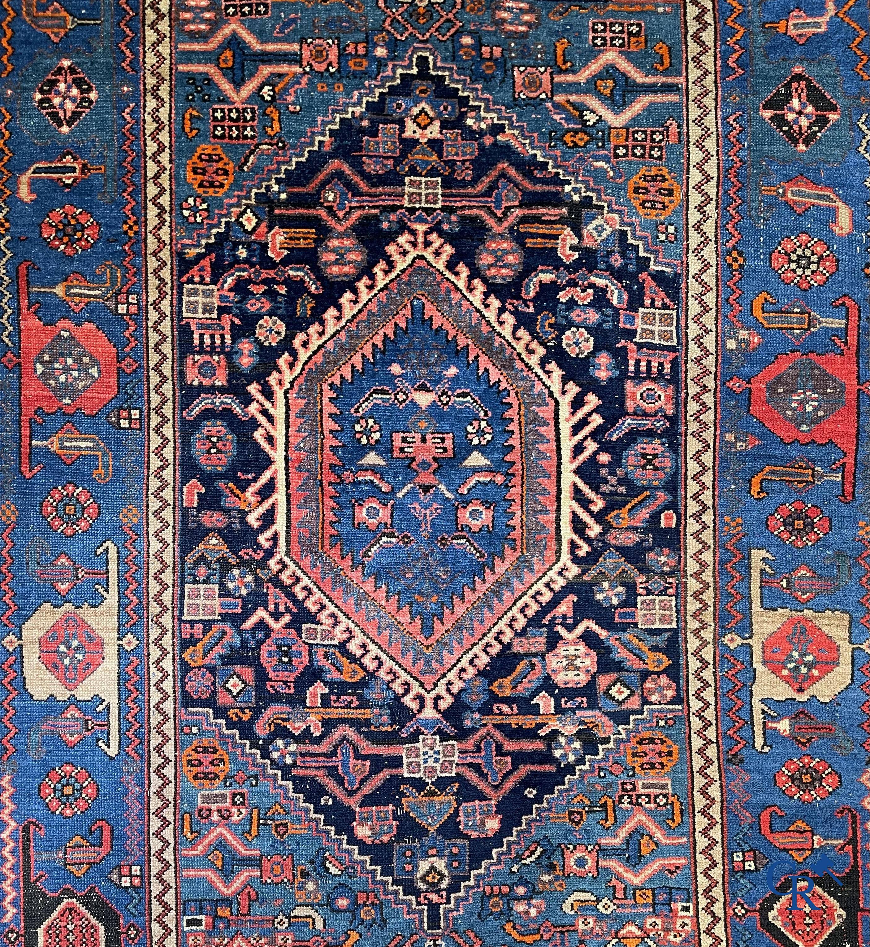 Antique Oriental carpets, an antique hand-knotted carpet with motifs on a blue background.