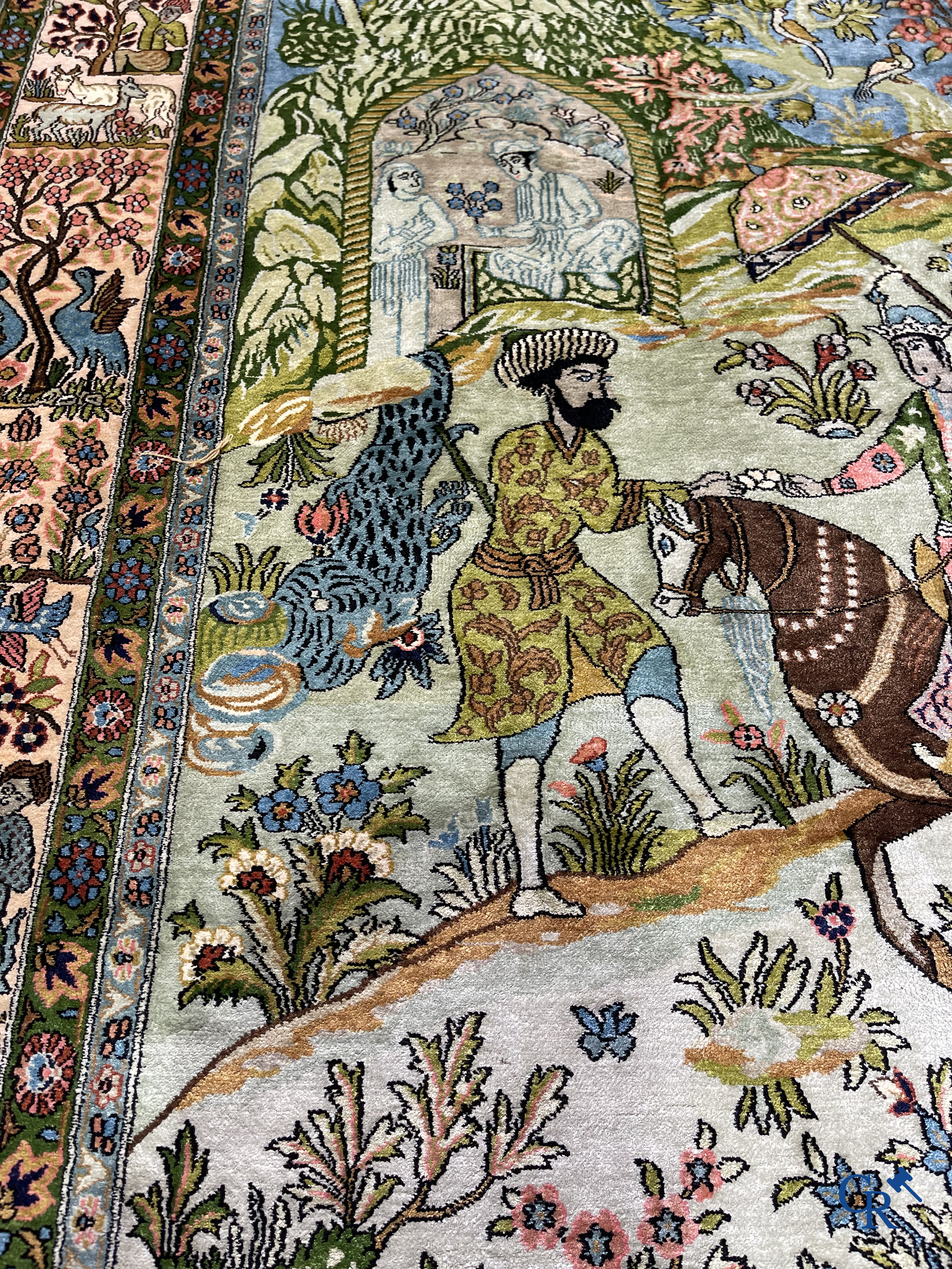 Tapis d'Orient. Iran. Un tapis persan en soie finement noué à la main avec des personnages et un cheval dans un paysage.