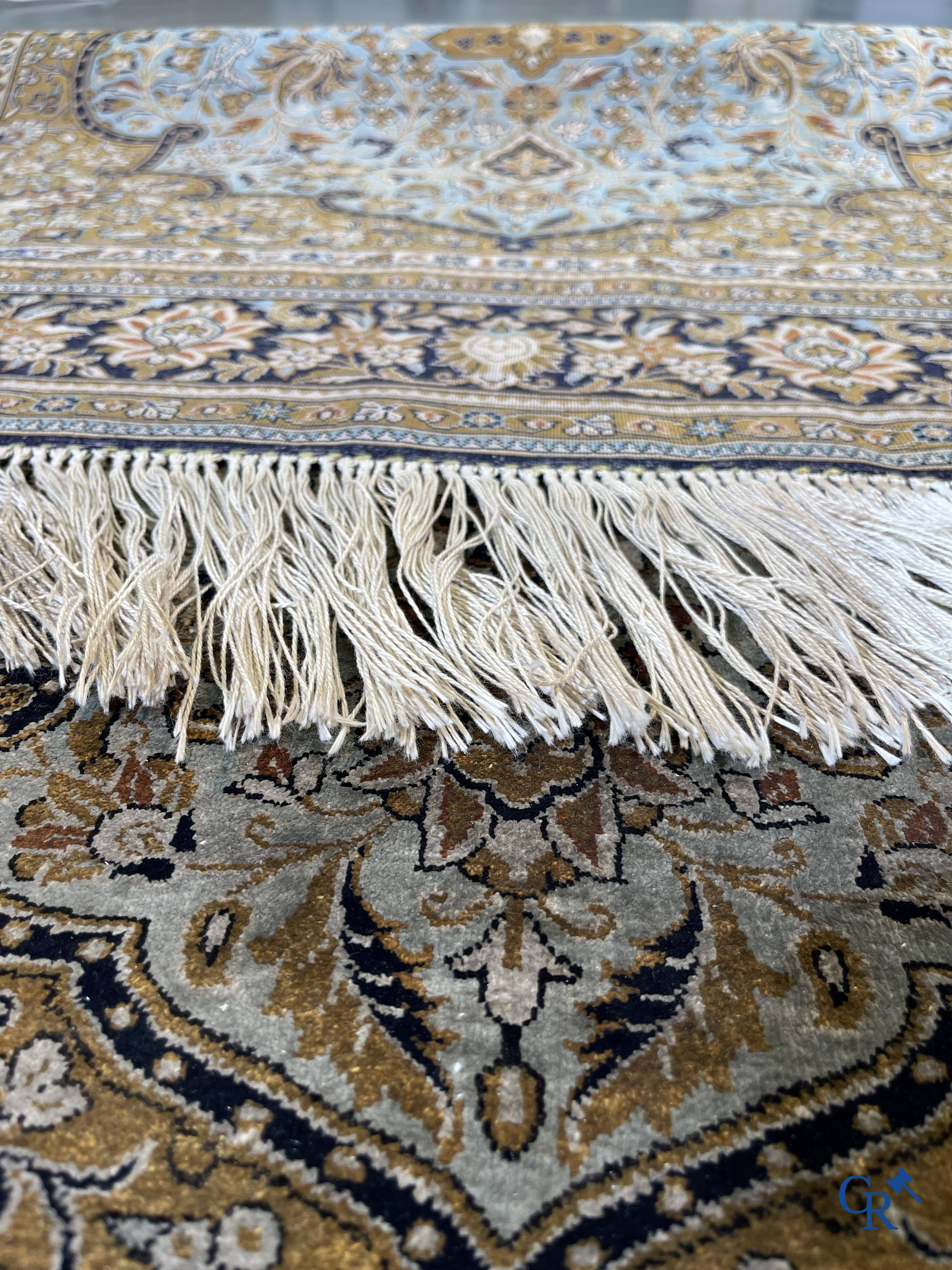 Tapis d'Orient. Un tapis en soie finement noué à la main avec un décor floral.