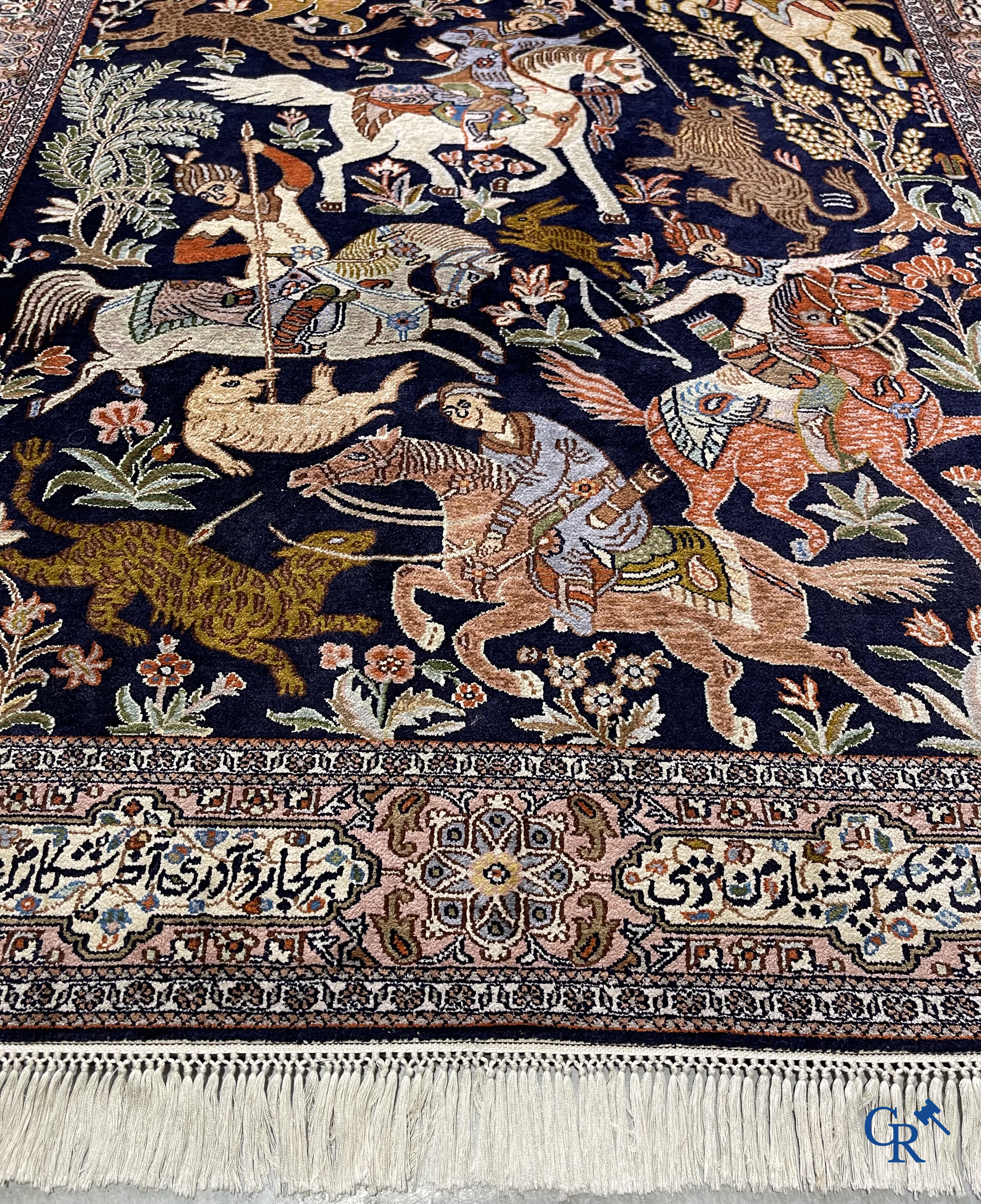 Oriental rugs. Iran. A finely hand-knotted Persian rug in wool and silk with hunters on horseback and inscriptions.