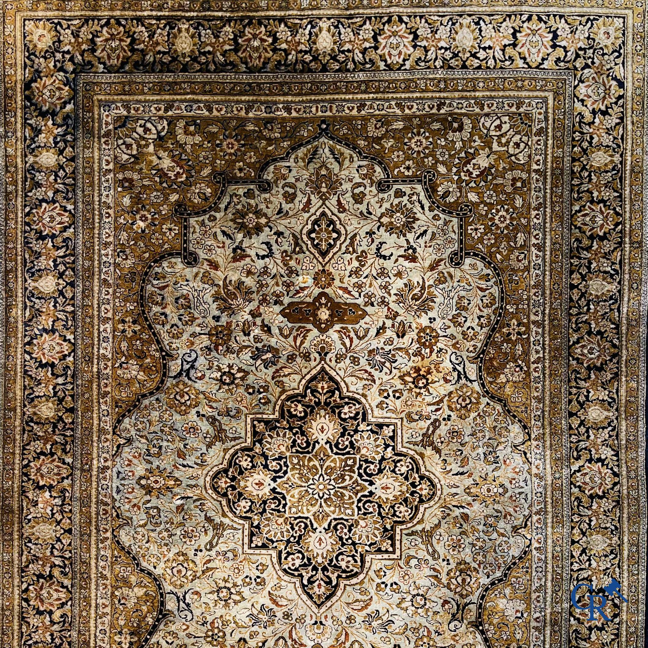 Tapis d'Orient. Un tapis en soie finement noué à la main avec un décor floral.