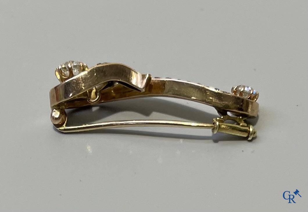 Juwelen, een kleine broche in goud 585°/00 bezet met briljanten.