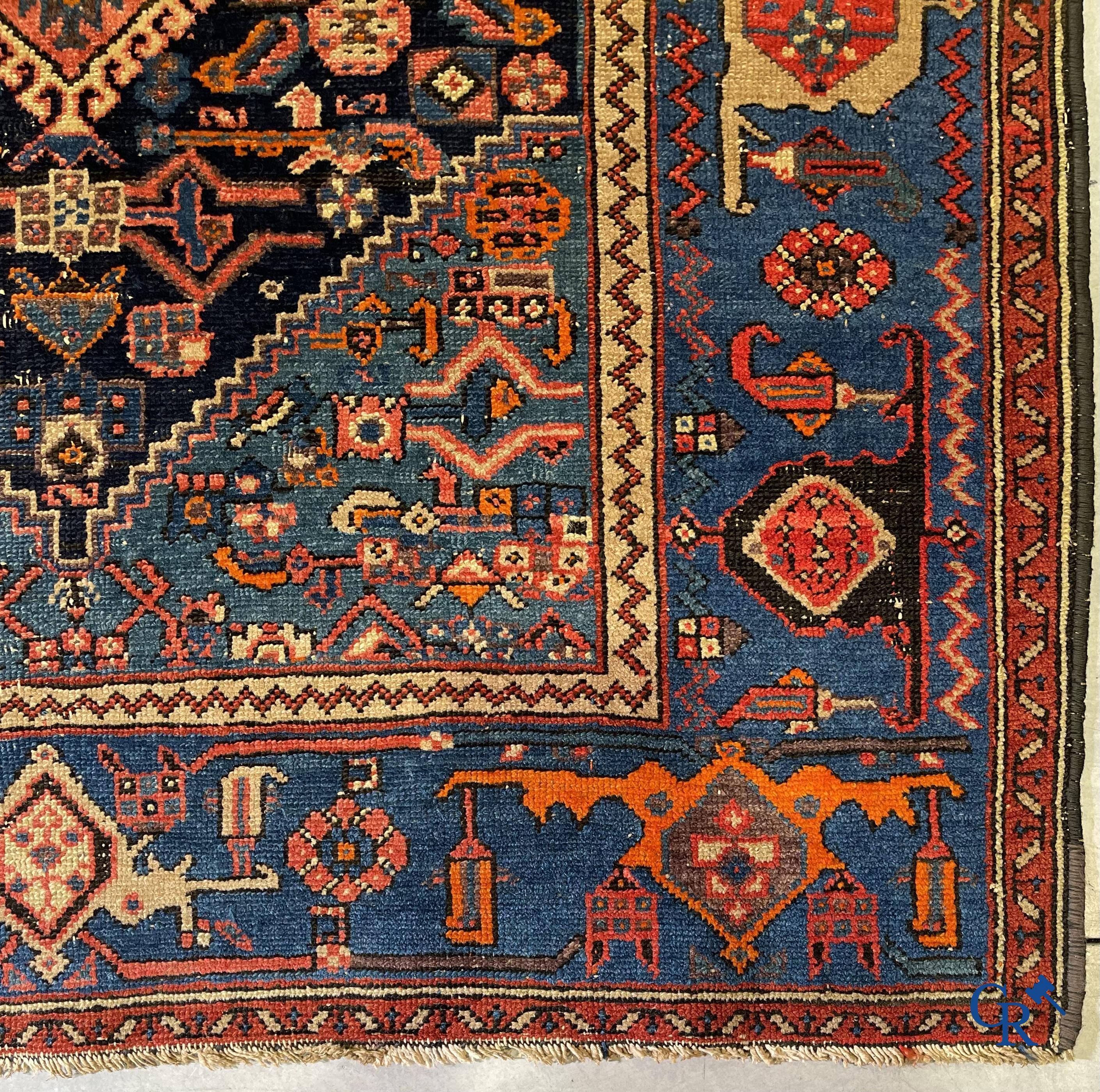 Antique Oriental carpets, an antique hand-knotted carpet with motifs on a blue background.