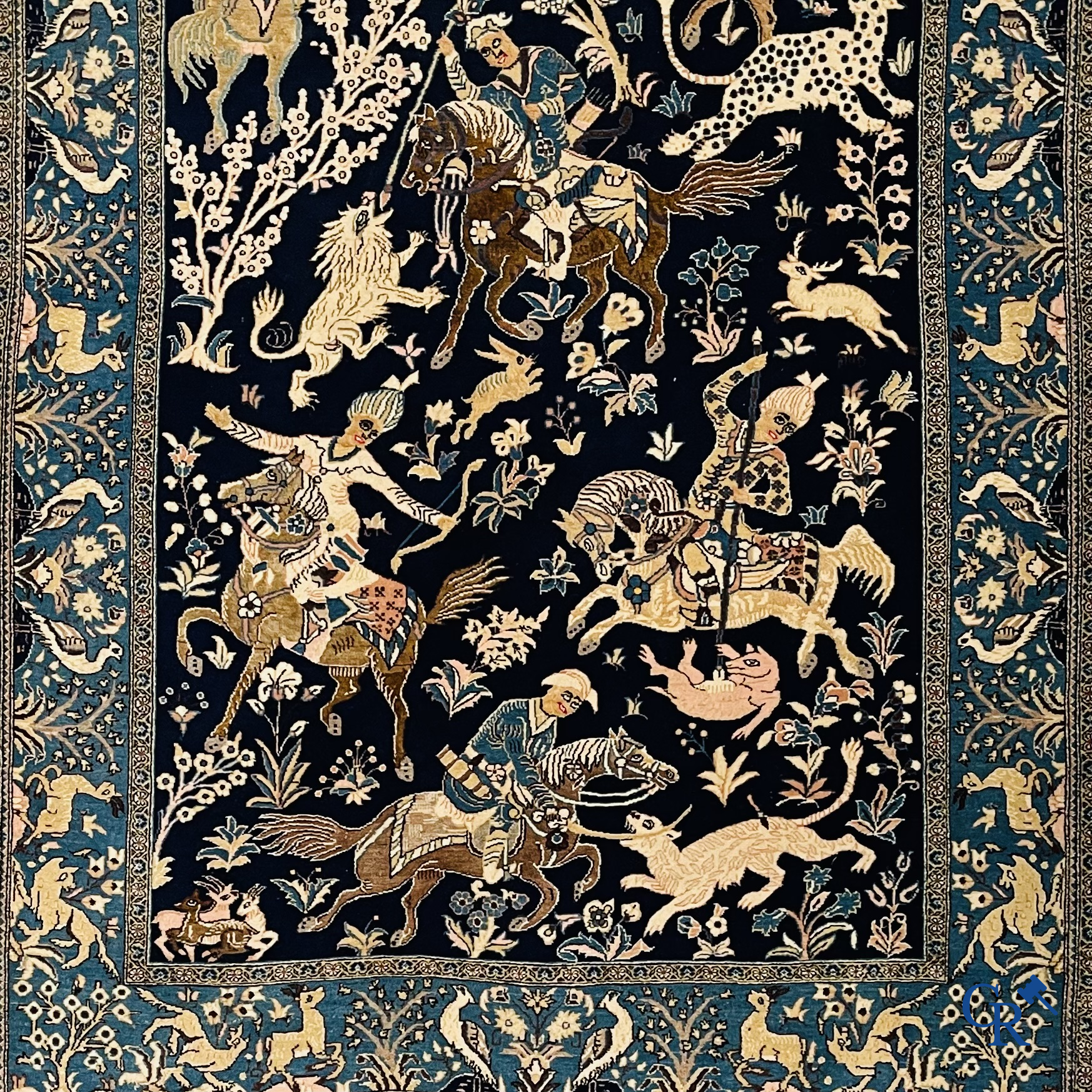 Oosterse tapijten. Ghoum, een fijn geknoopt Perzisch tapijt met ruiters te paard op een donkerblauwe achtergrond.