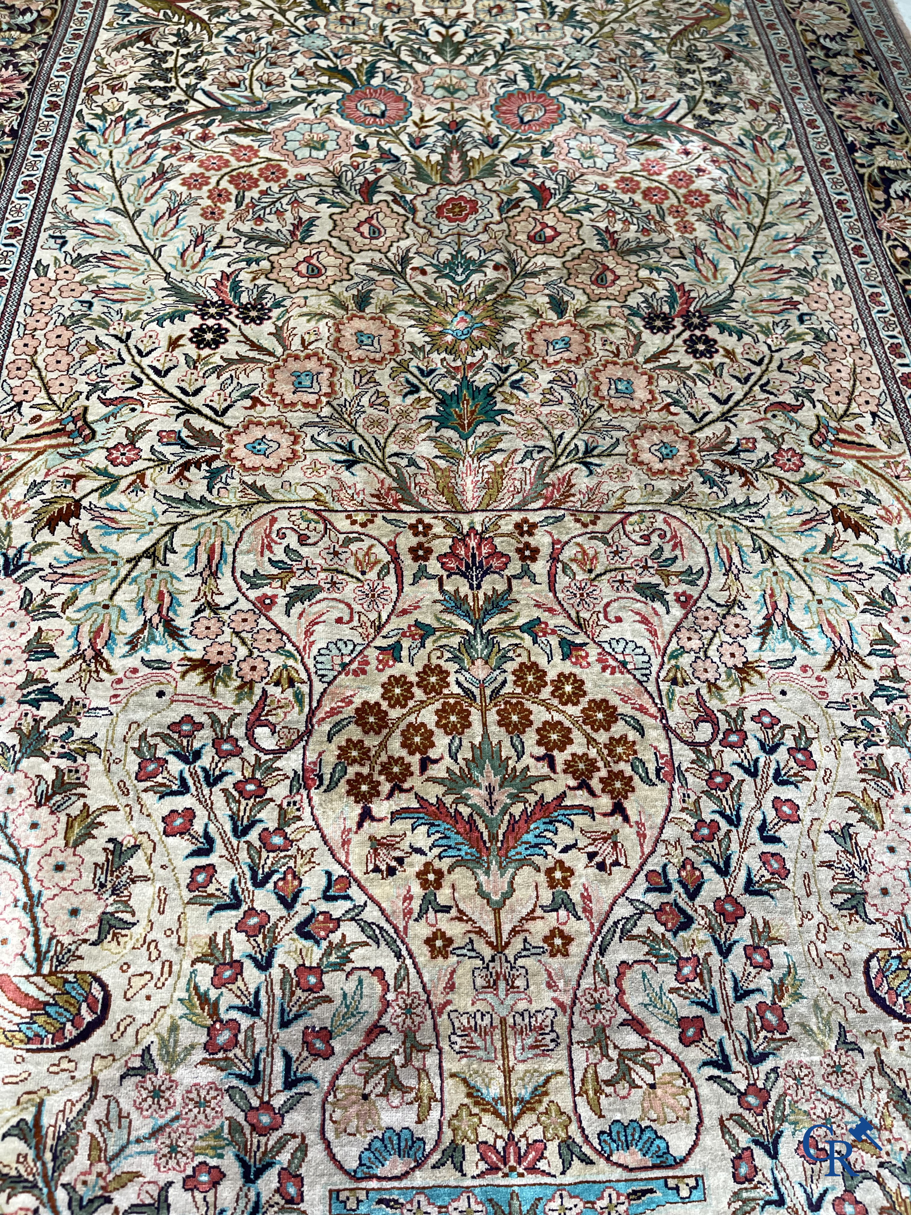 Tapis d'Orient: Un tapis persan en soie finement noué à la main avec un vase à fleurs et des oiseaux dans un décor floral.