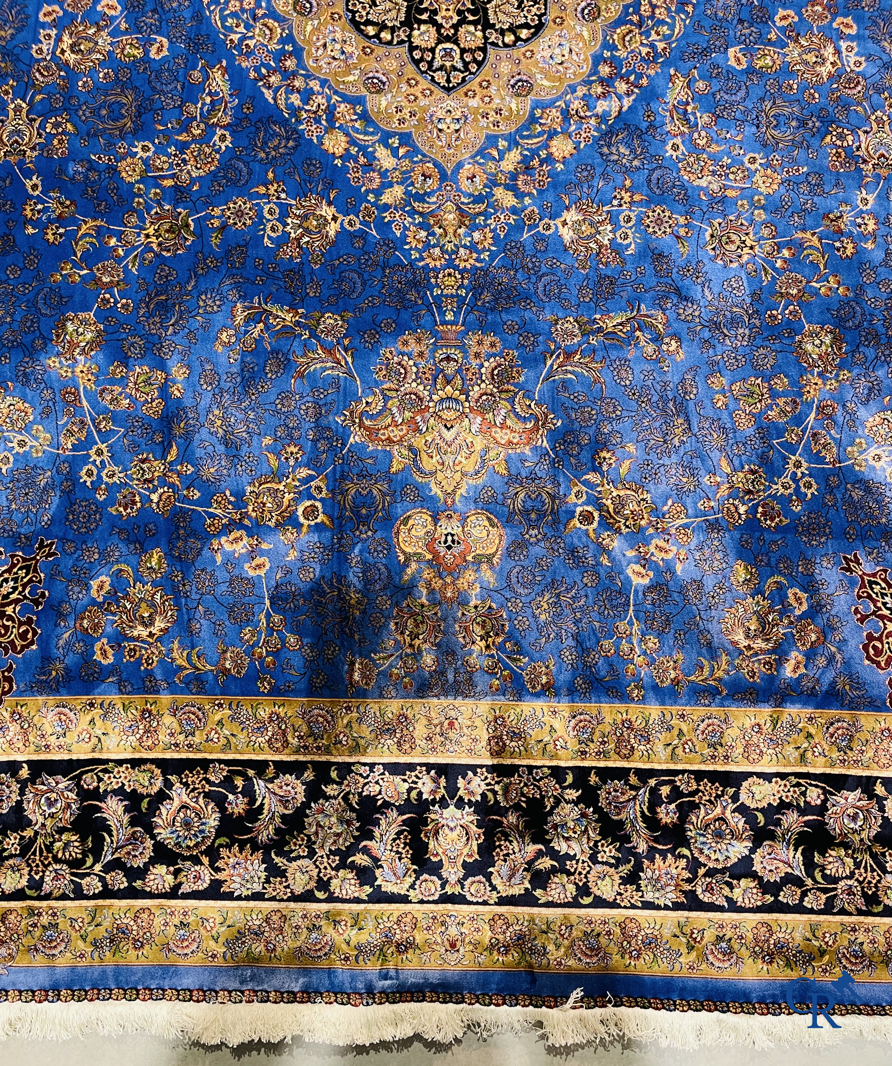 Tapis. Exceptionnel tapis en soie avec un décor floral sur fond bleu.